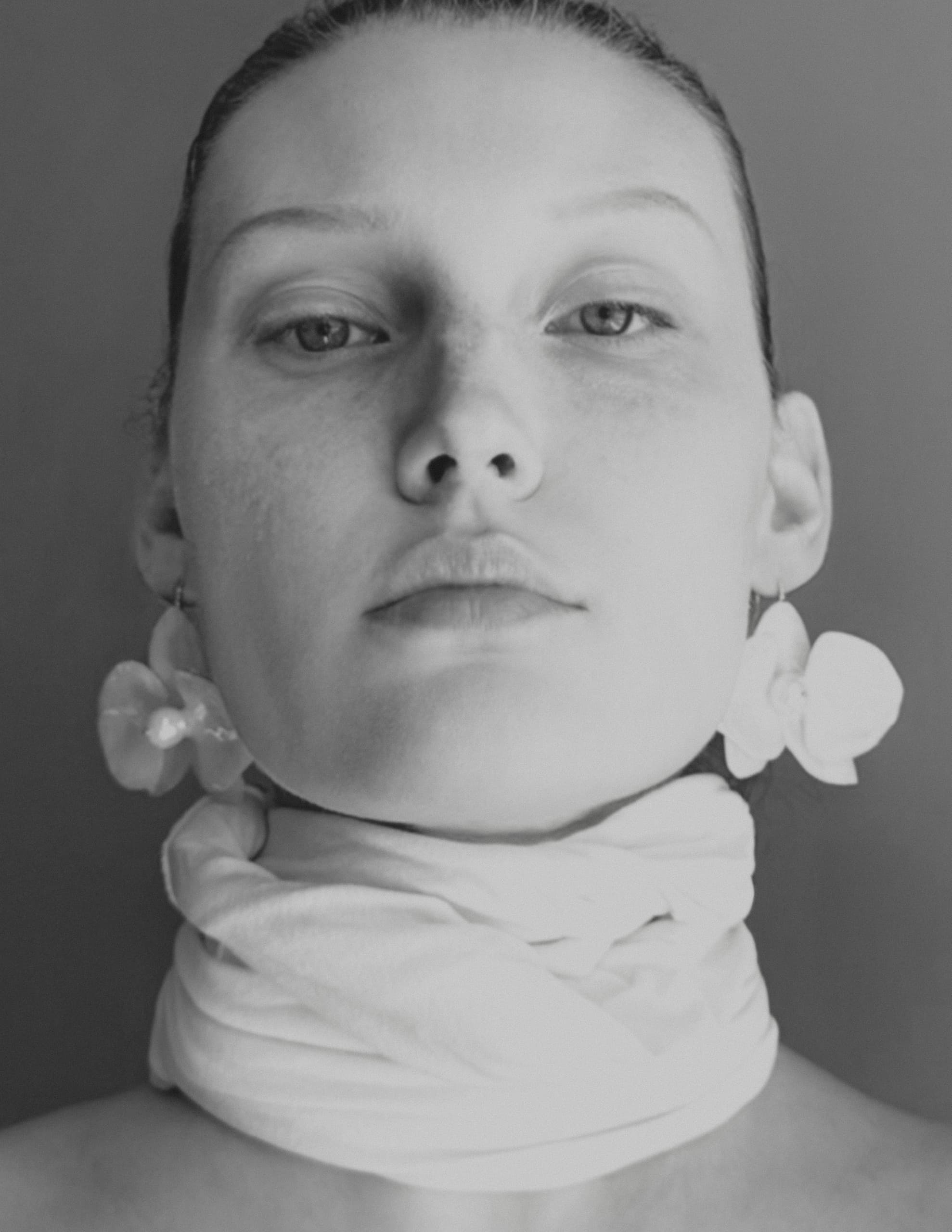 Portrait of a woman with floral earrings and a scarf, black and white photography.