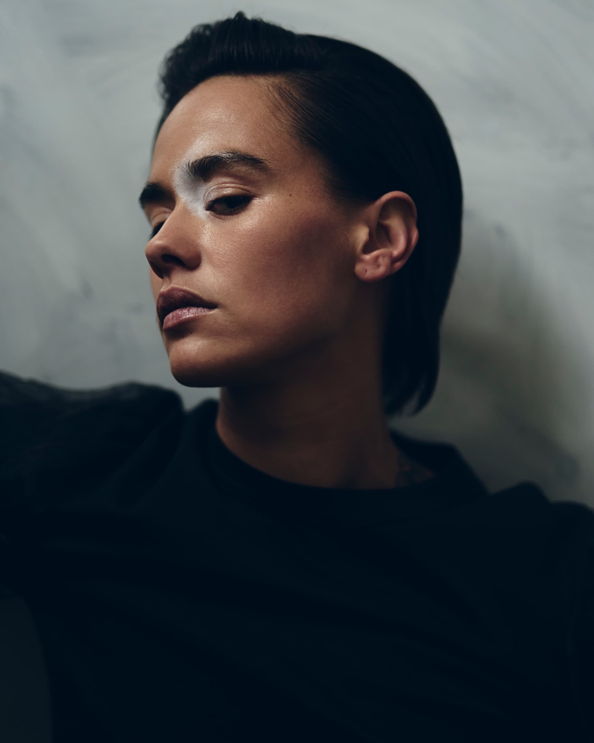 Thoughtful person with dark hair against a neutral background.