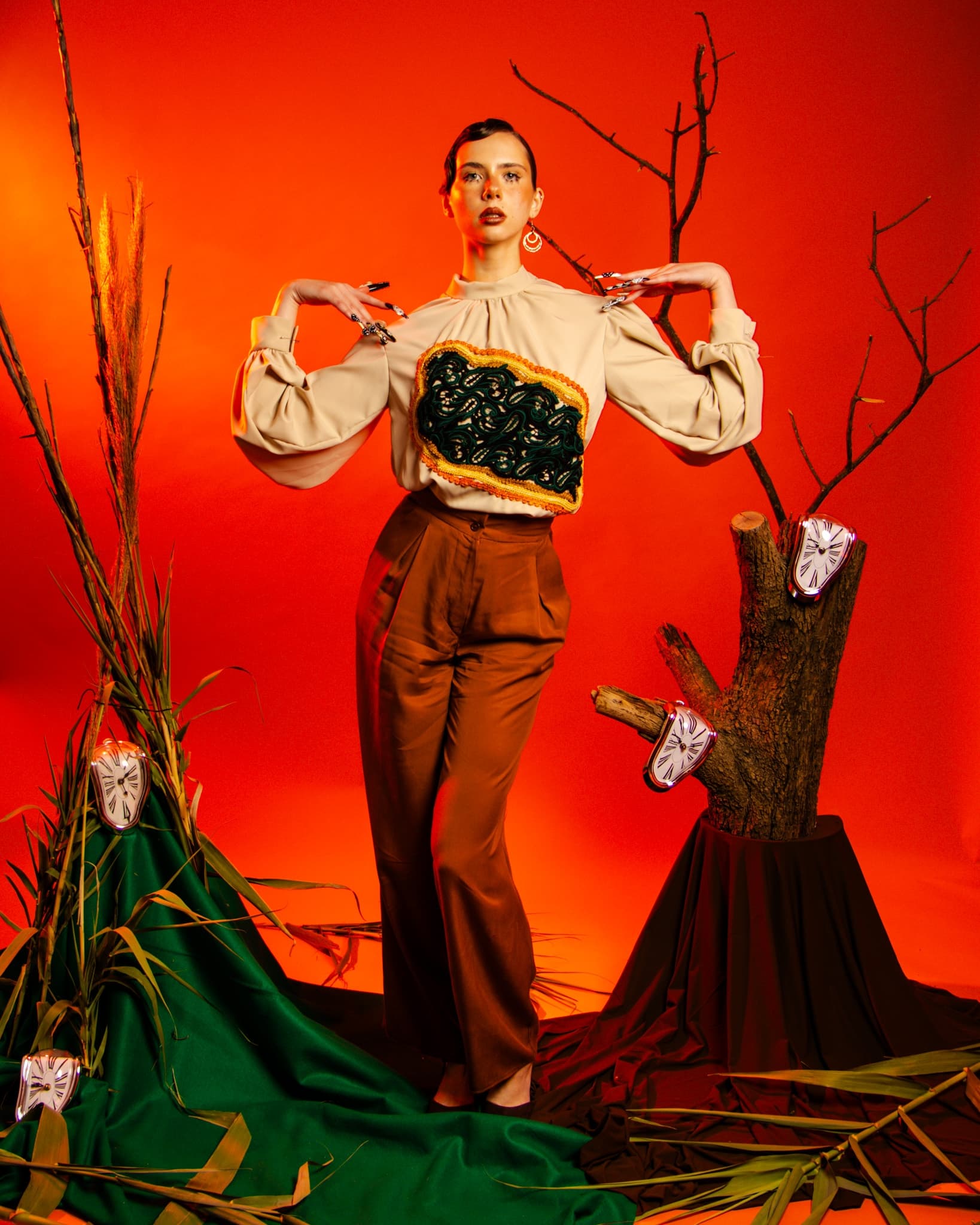 Fashion model poses in eclectic outfit amid surreal orange and green backdrop.