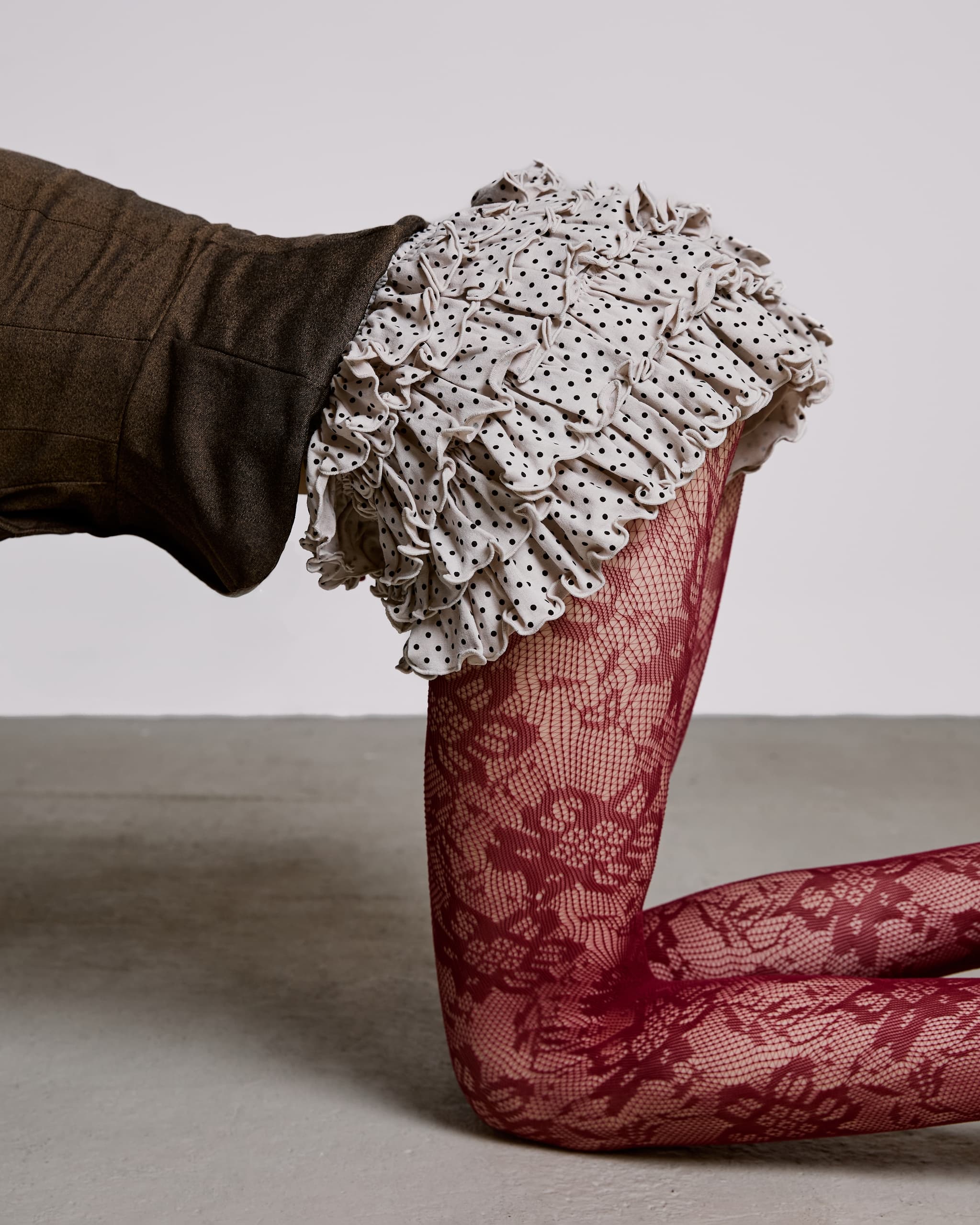 Ruffled skirt and lace tights fashion, artistic pose on gray background.