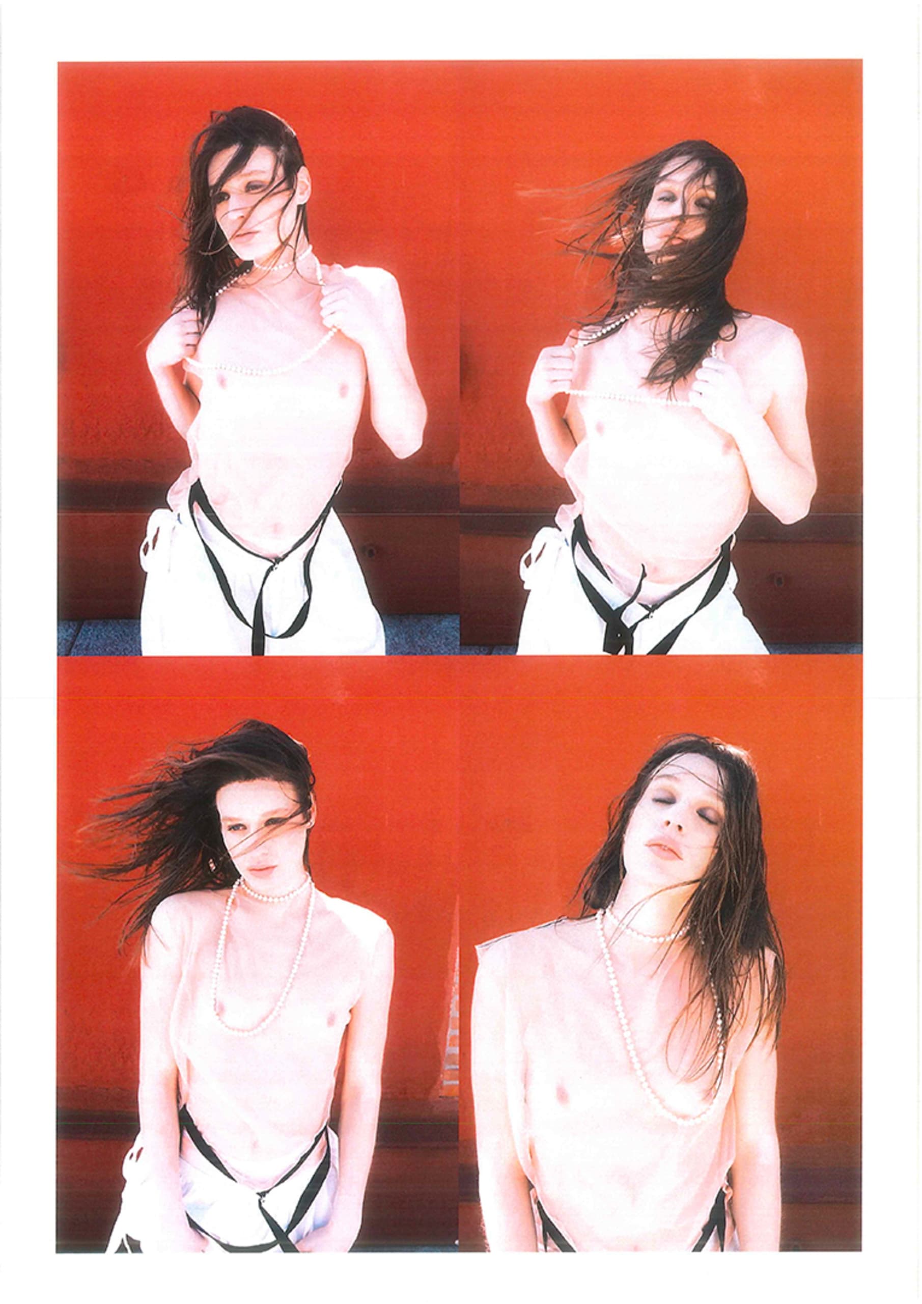 Fashion photoshoot with model against vibrant red background, wearing pearls.
