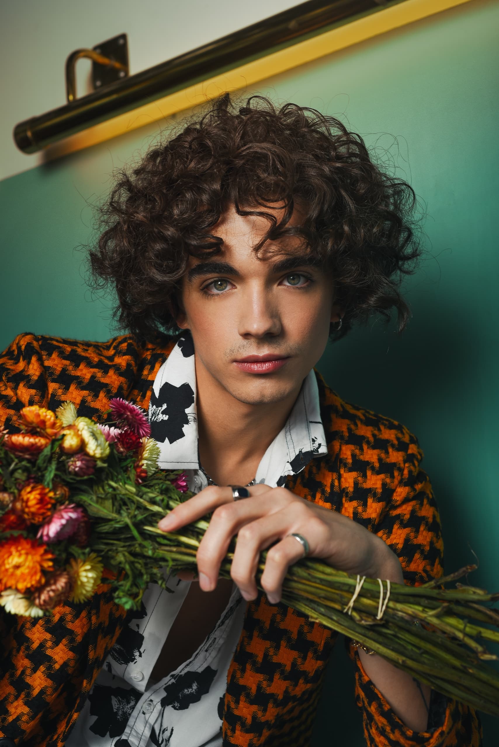 Person holding a colorful bouquet, wearing a stylish orange houndstooth jacket.