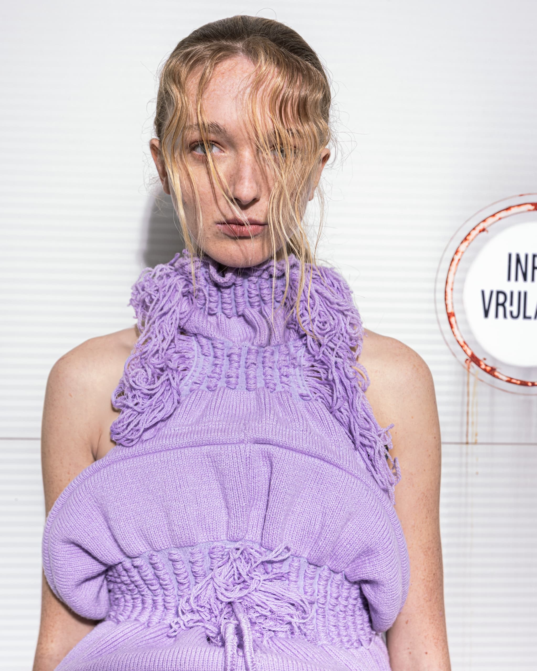 Model in a textured purple knit outfit at a fashion event.