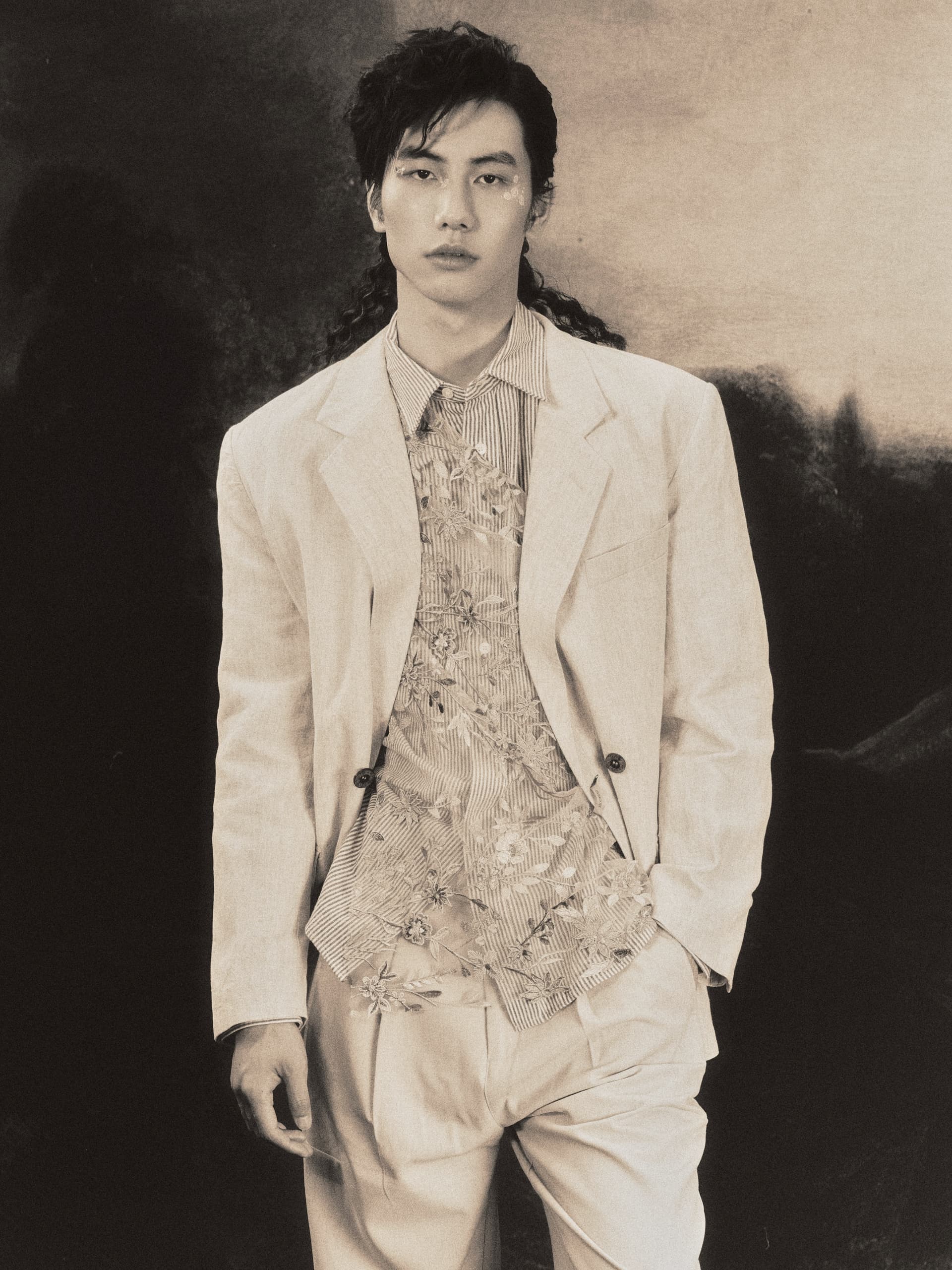 Man in vintage suit with floral patterns, portrait style, sepia tone photography.