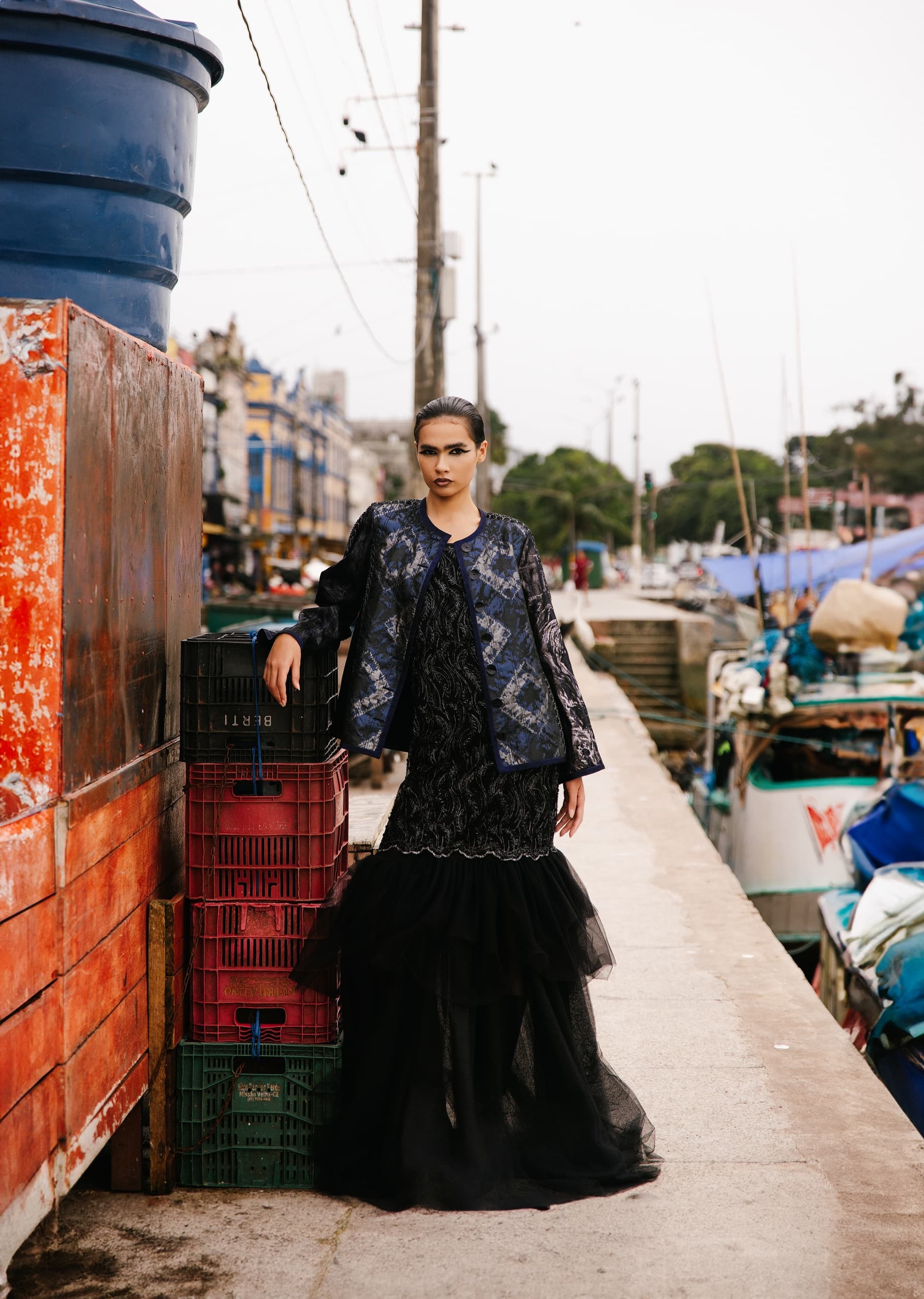 Fashionable woman in elegant black outfit by urban waterfront.