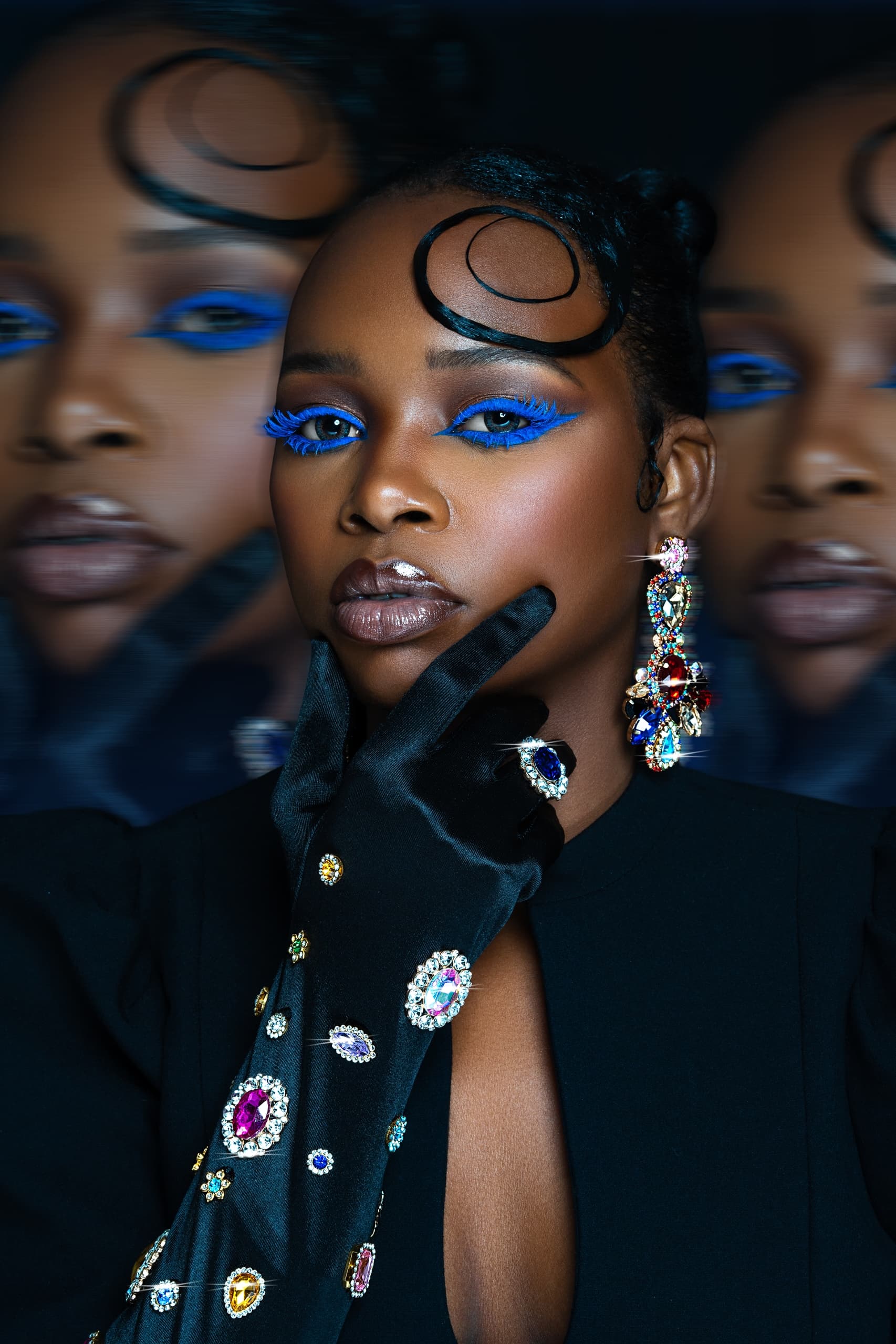 Elegant woman with bold blue eye makeup and jeweled gloves.