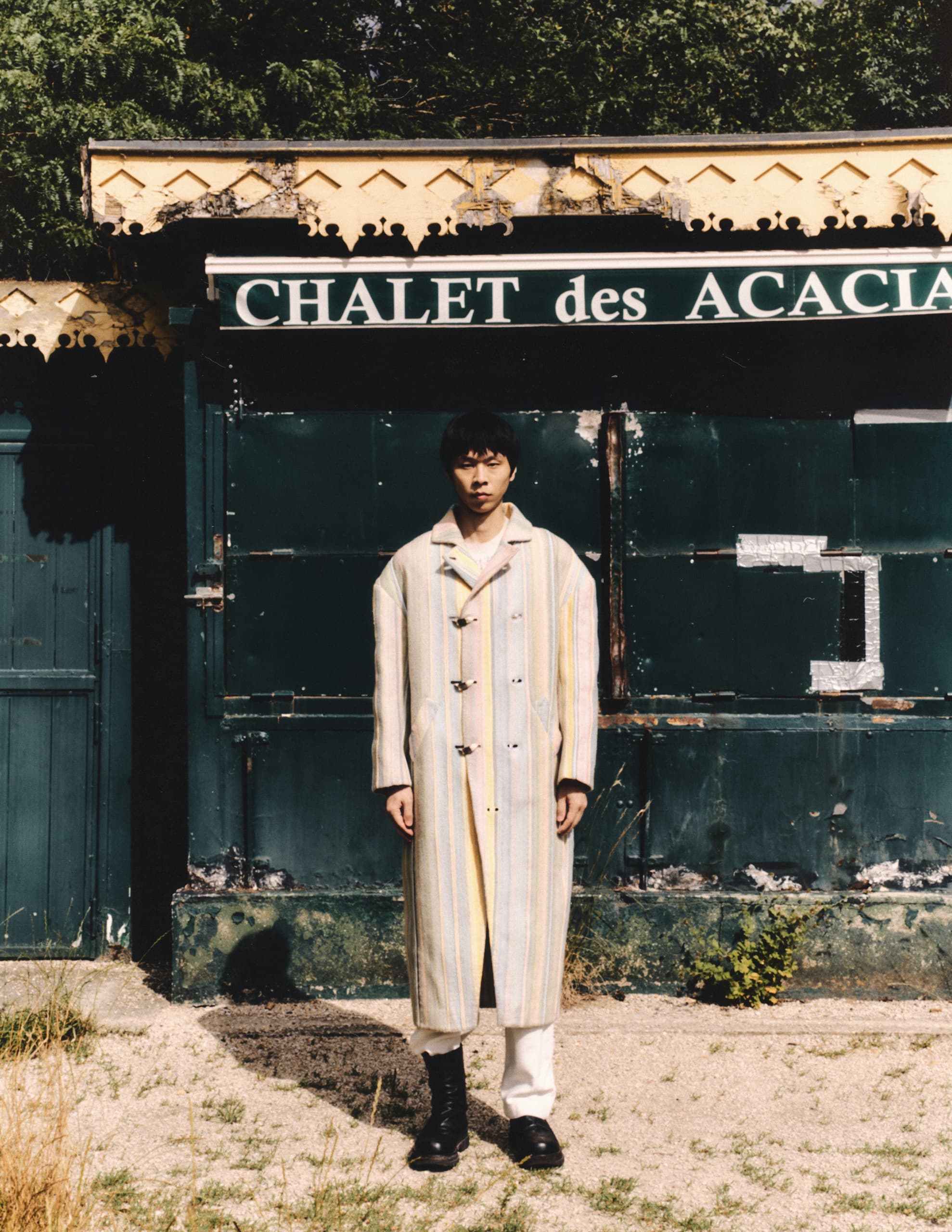 Man in a long coat standing at Chalet des Acacias entrance.