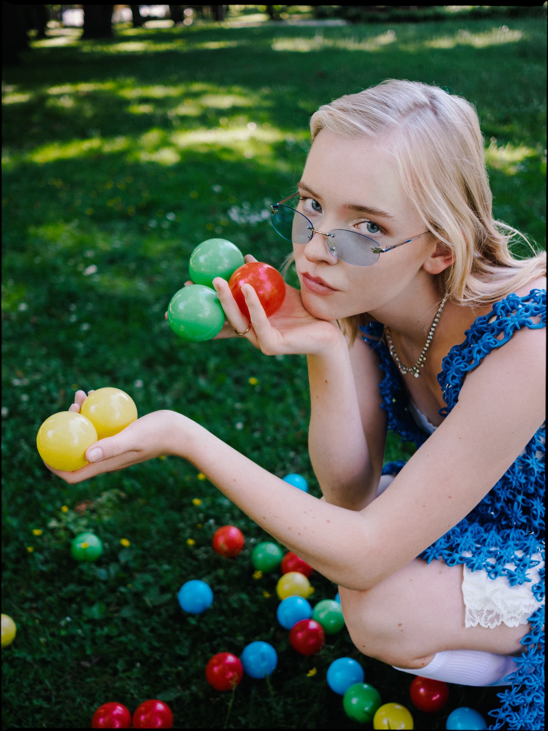 Woman holding colorful balls outdoors in sunny park.