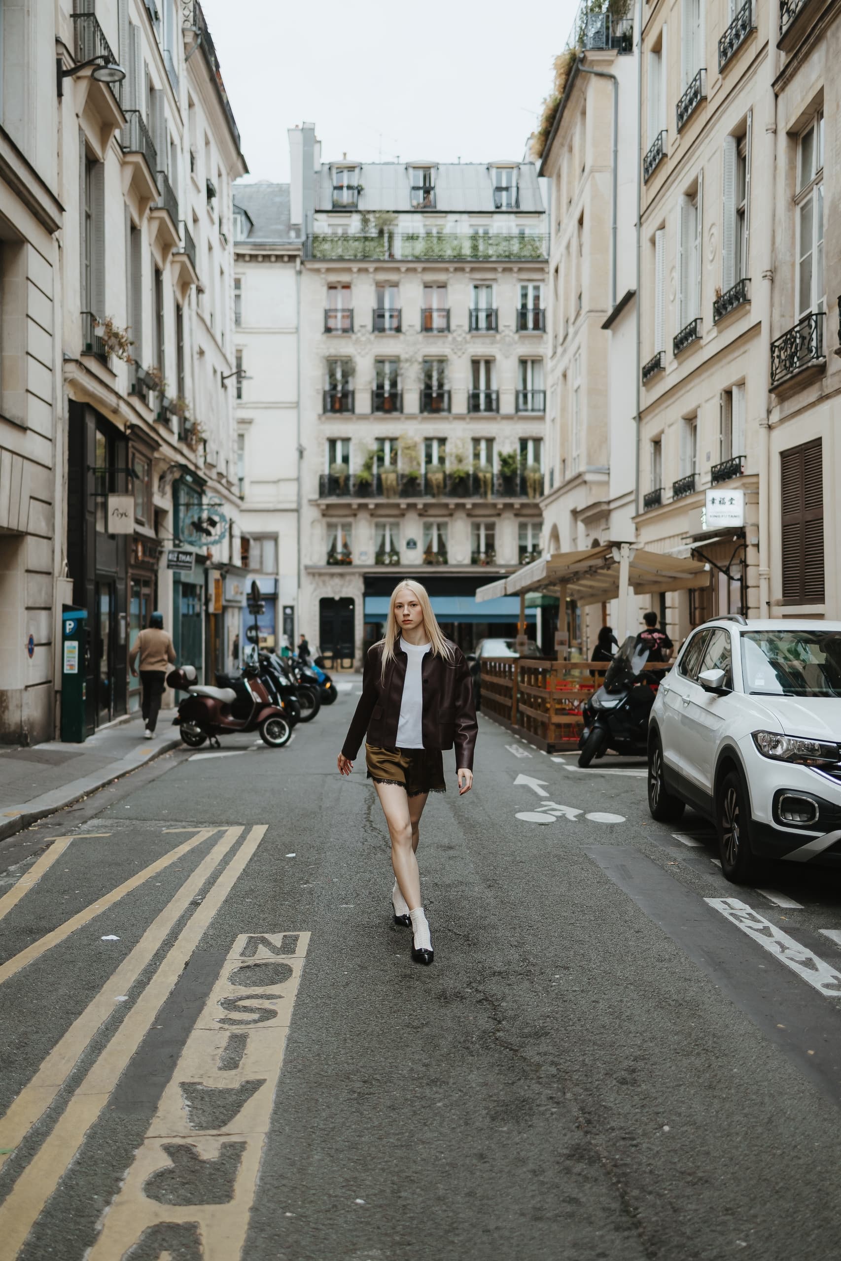Woman walking in stylish outfit on a chic Parisian street.