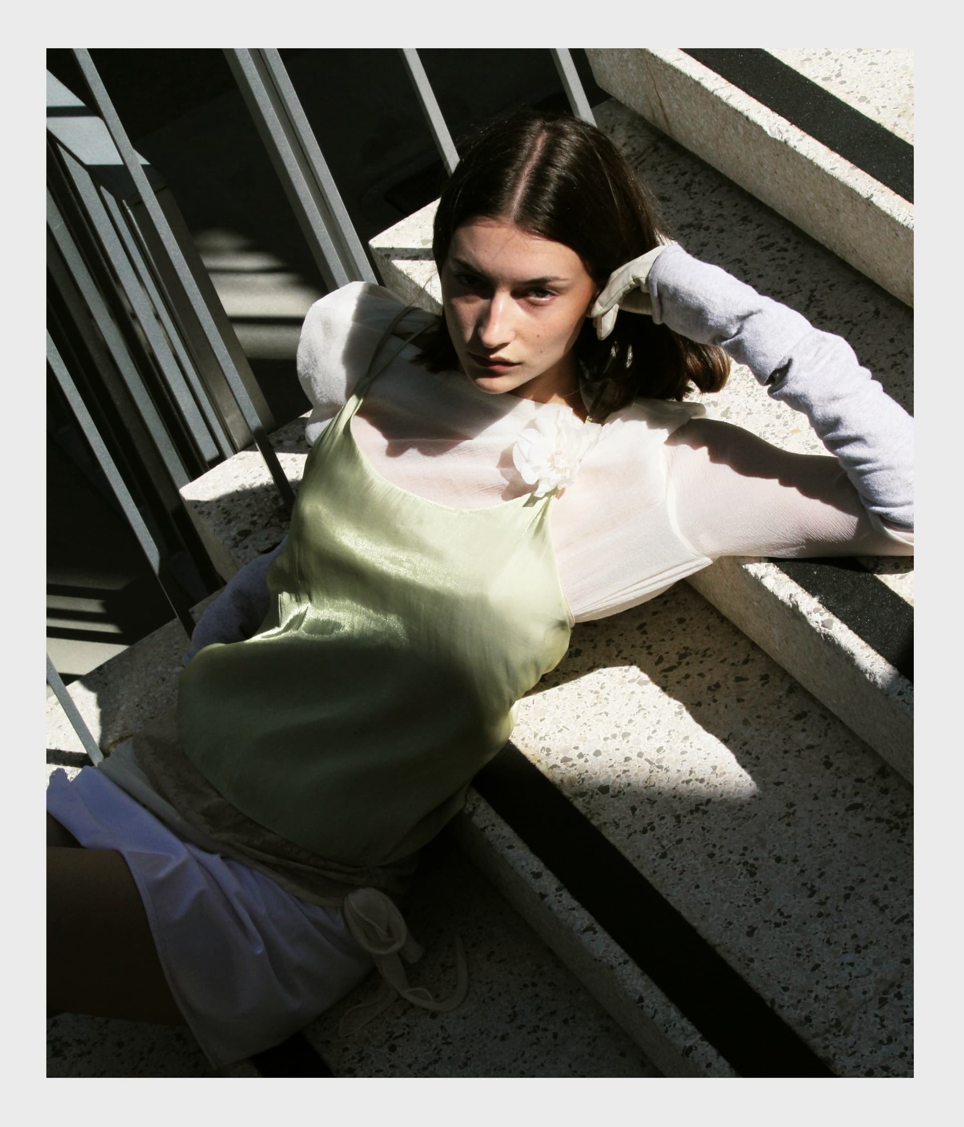 Woman in stylish outfit lounging on sunlit stairs.