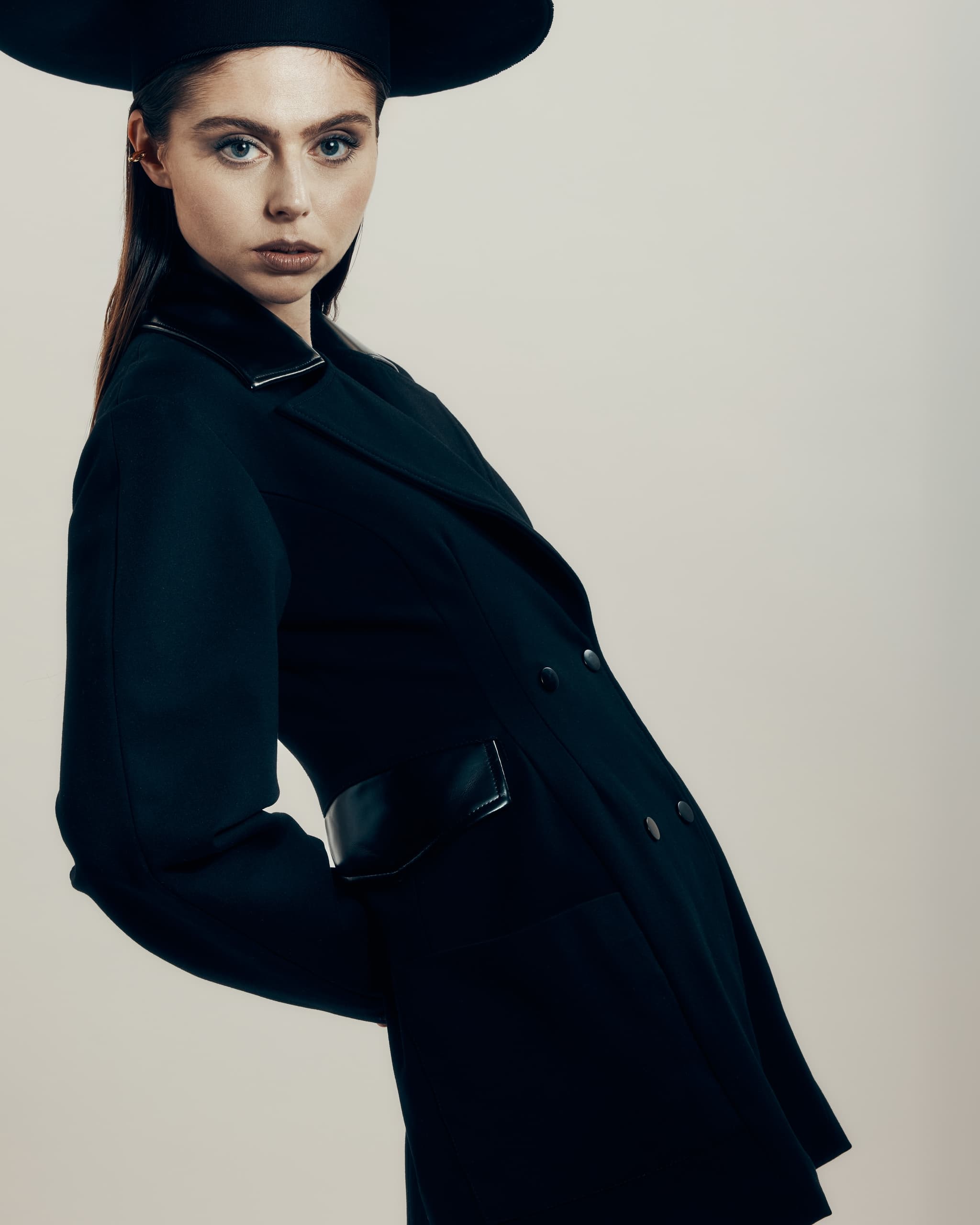 Fashion portrait of a stylish person in a black outfit with matching hat.