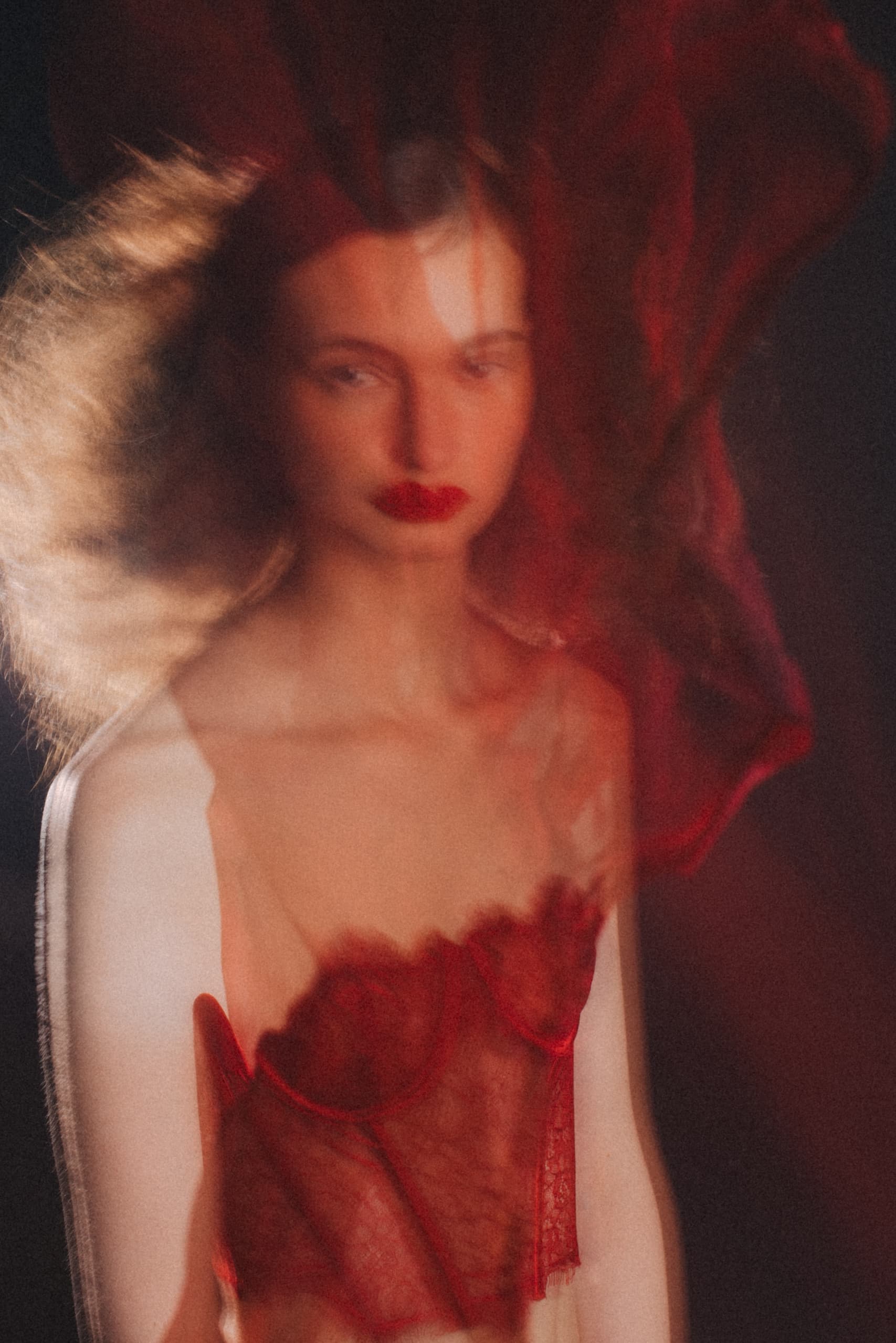 Artistic portrait of a woman in red lace with motion blur effect.