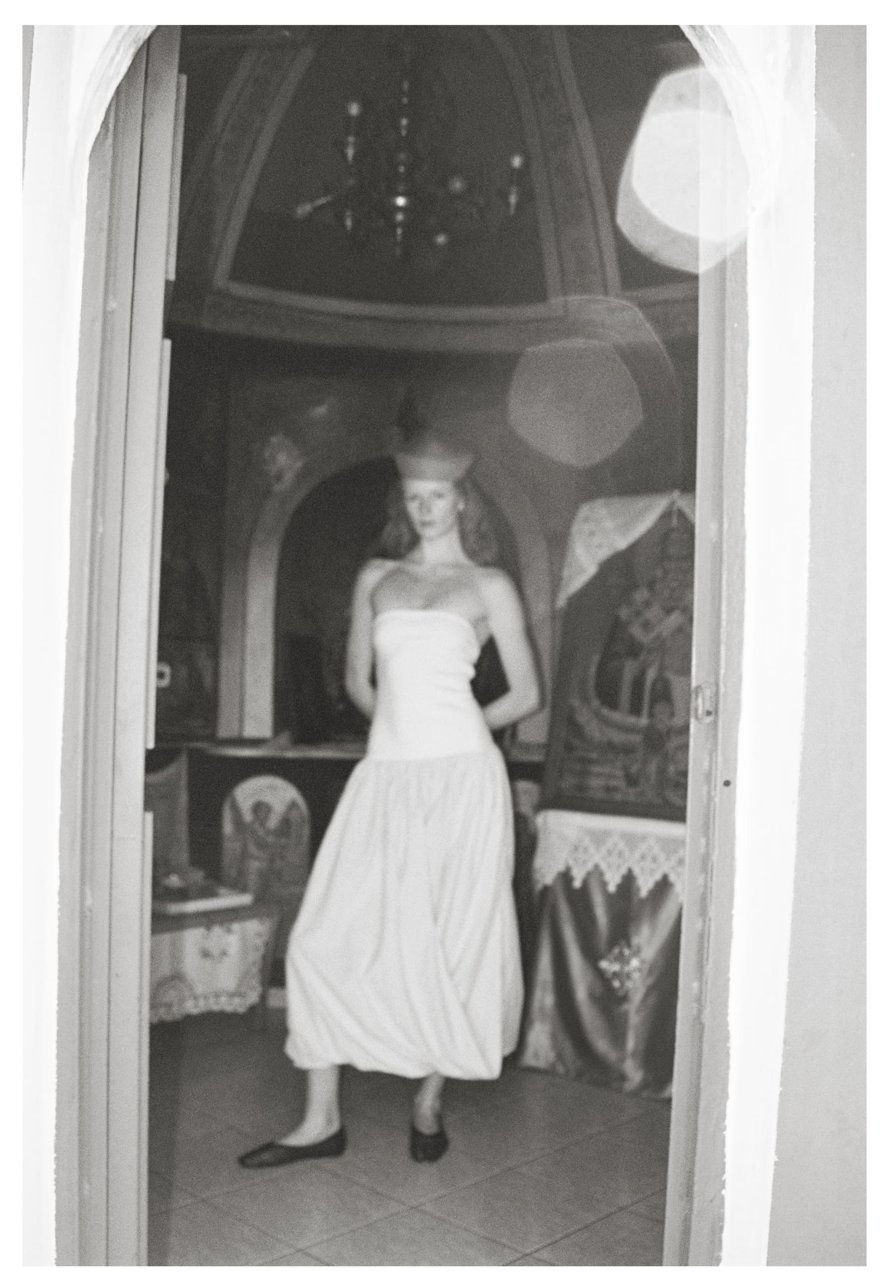 Vintage style photo of a woman in a dress standing in a dimly lit room.