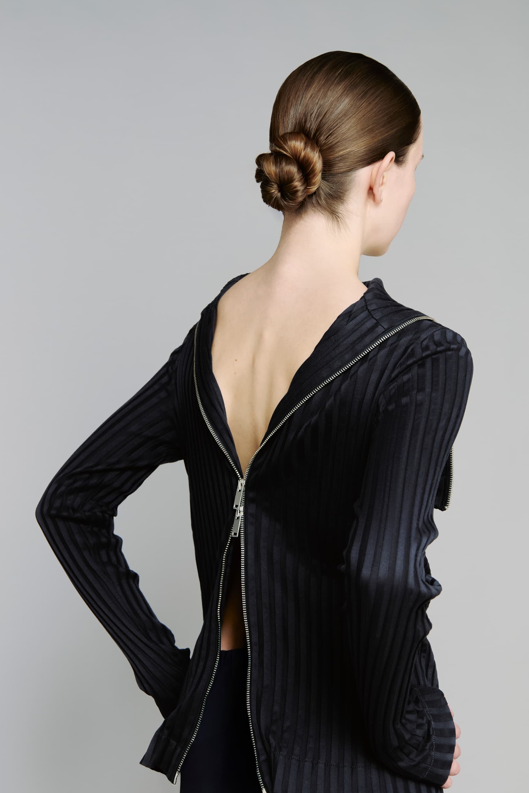Woman in a striped black dress with back zipper detail and elegant bun hairstyle.