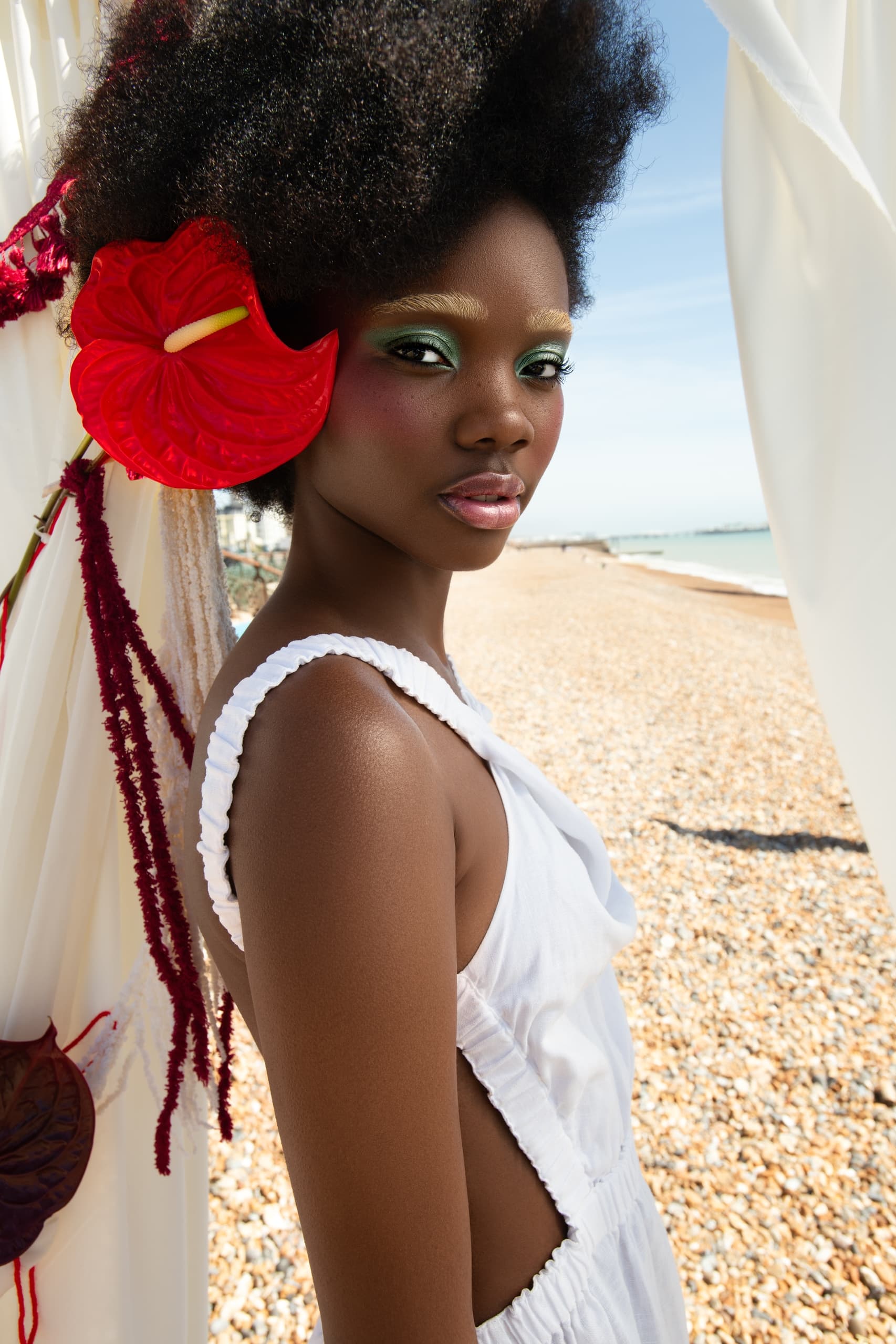 Stylish beach fashion with flower accessory and bold makeup.