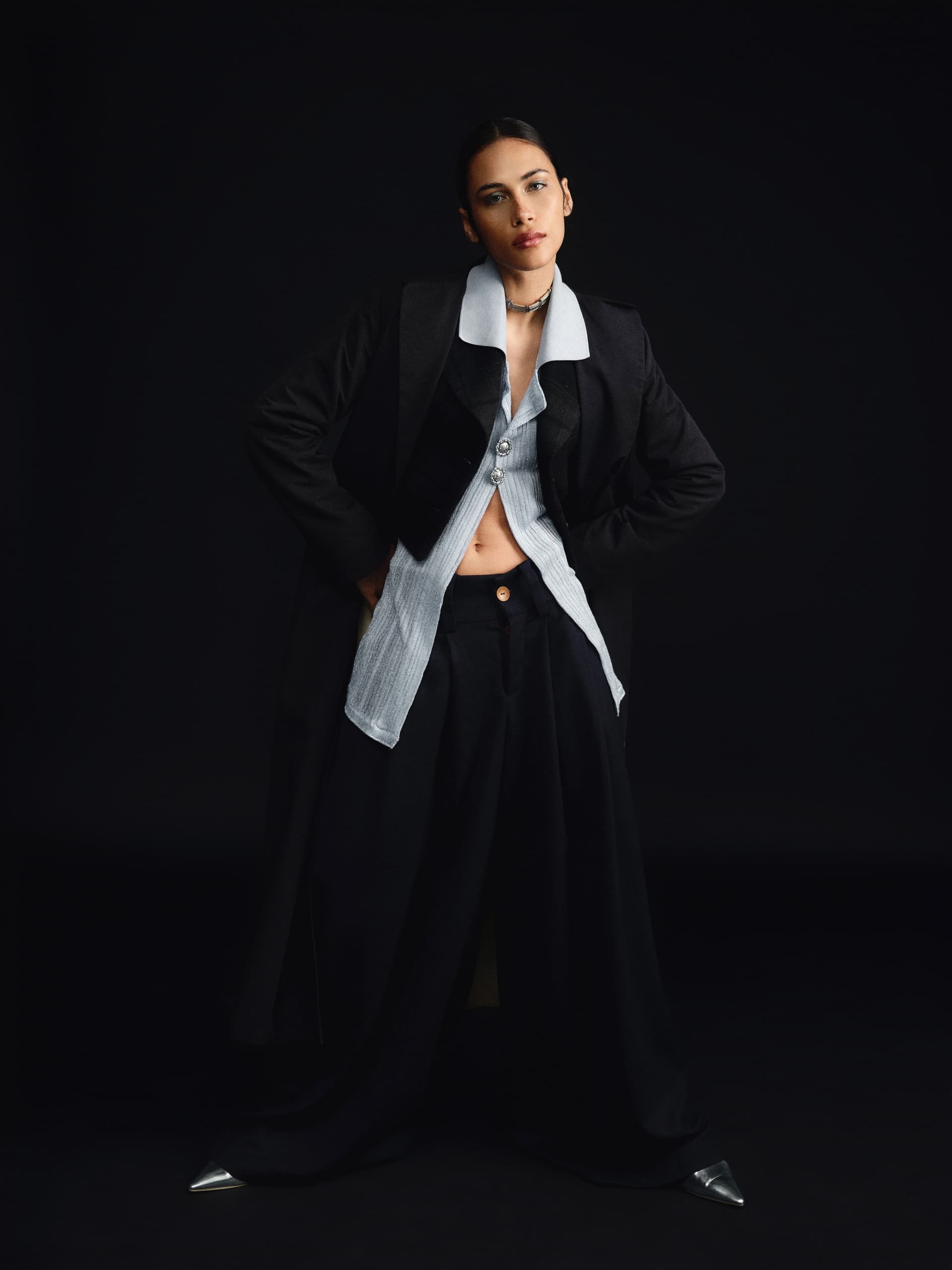 Chic woman in stylish layered black and white outfit against dark backdrop.