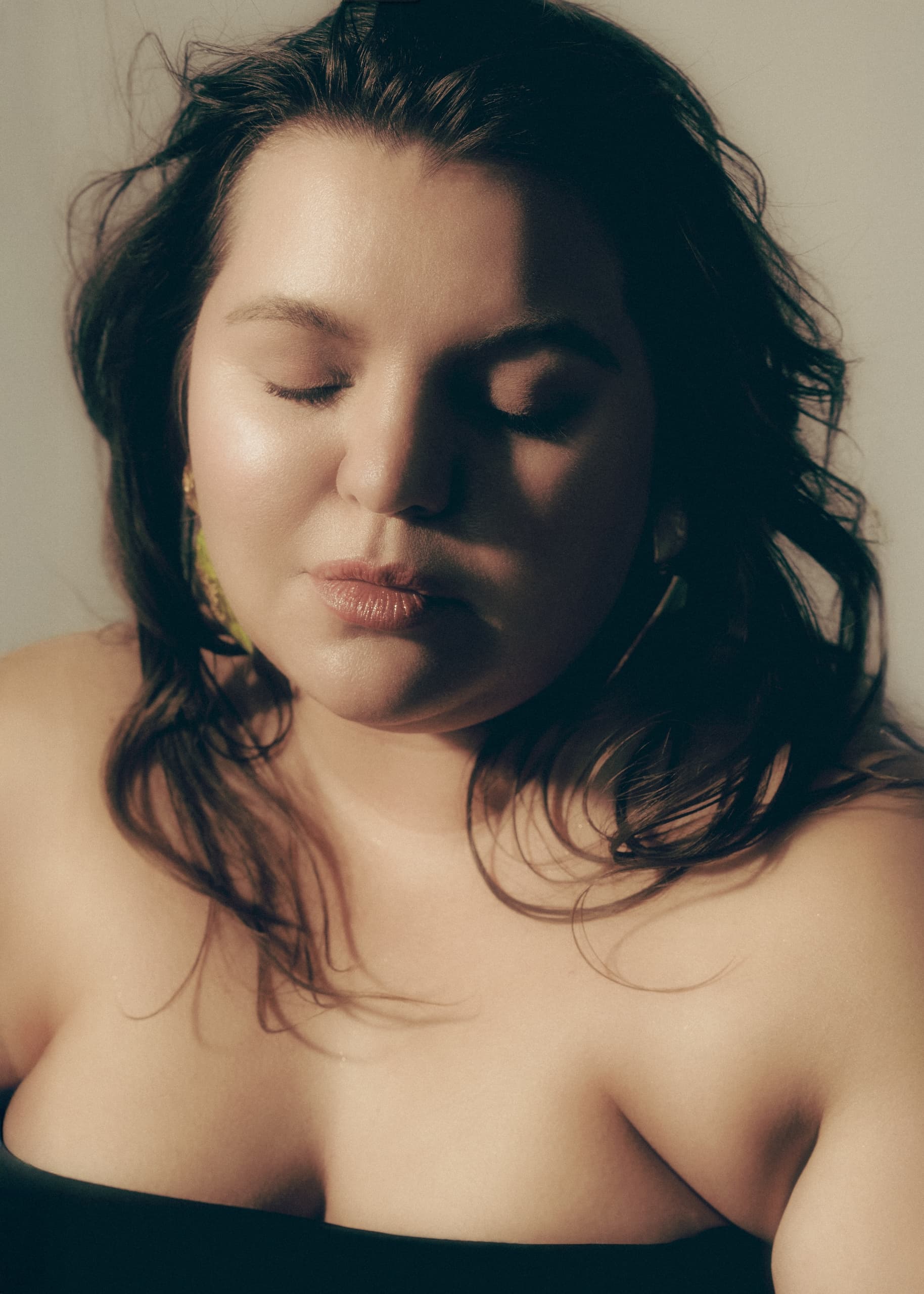 Woman with closed eyes, serene expression in soft light.