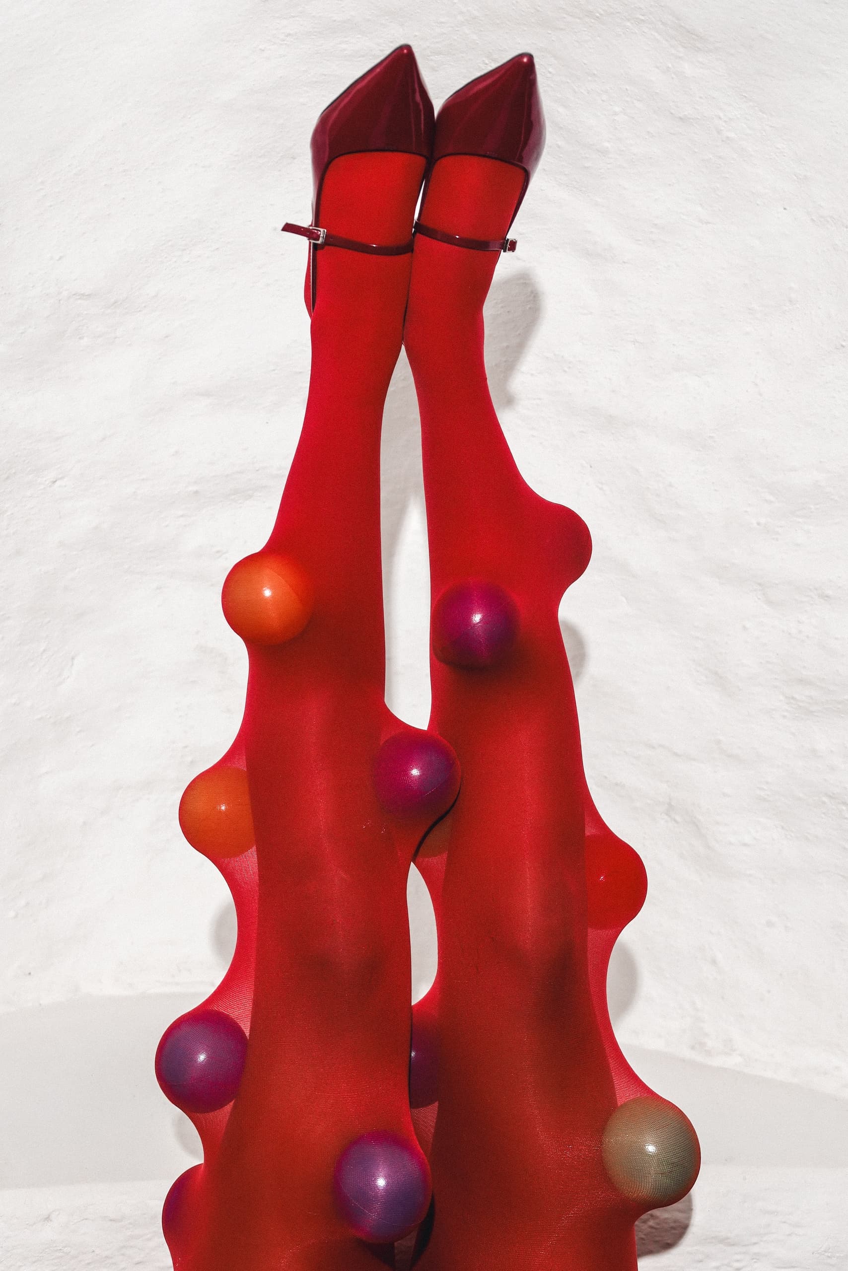 Red tights with colorful spheres and matching heels against a white background.