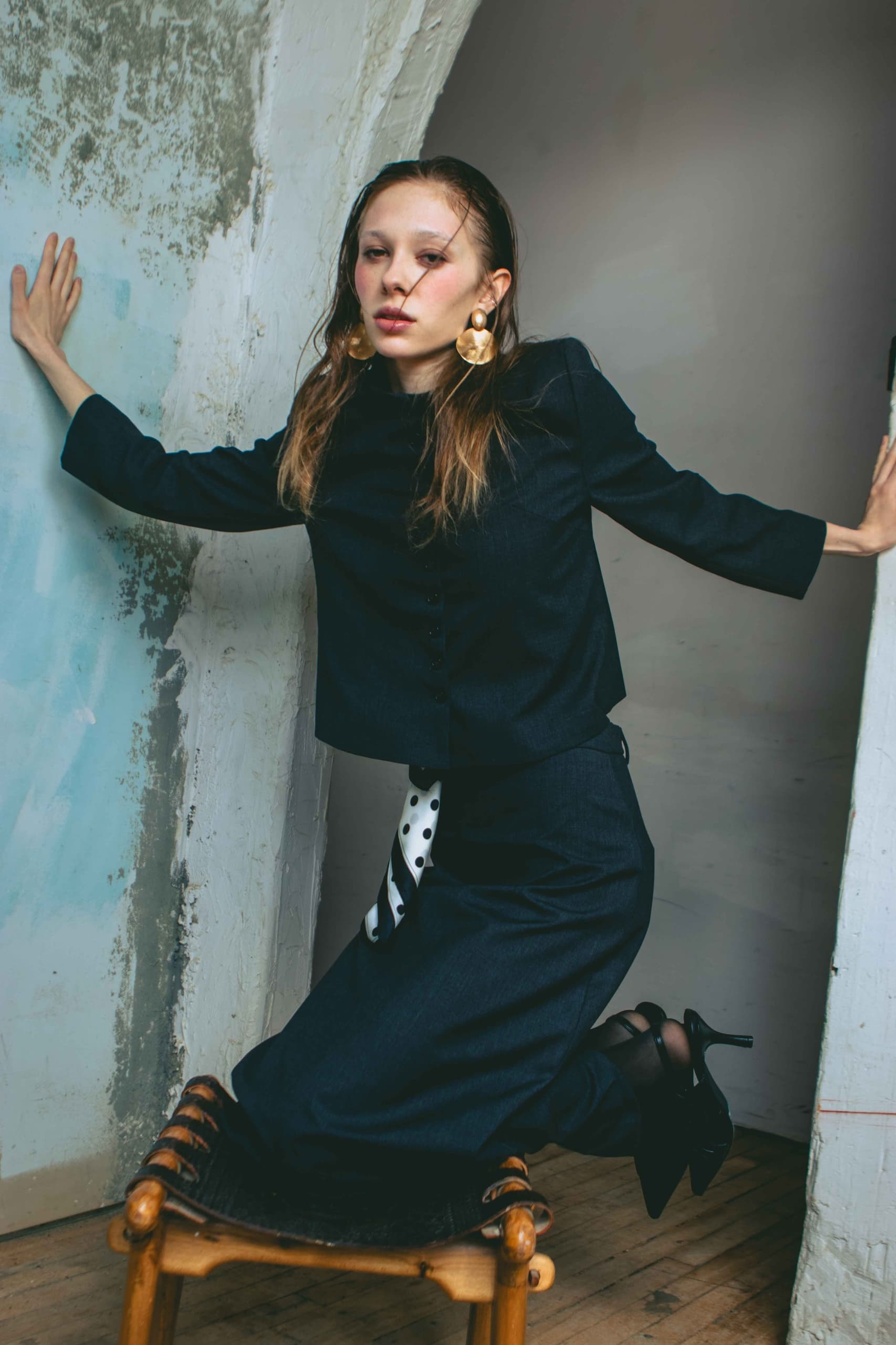 Fashion model in elegant black outfit posing indoors.