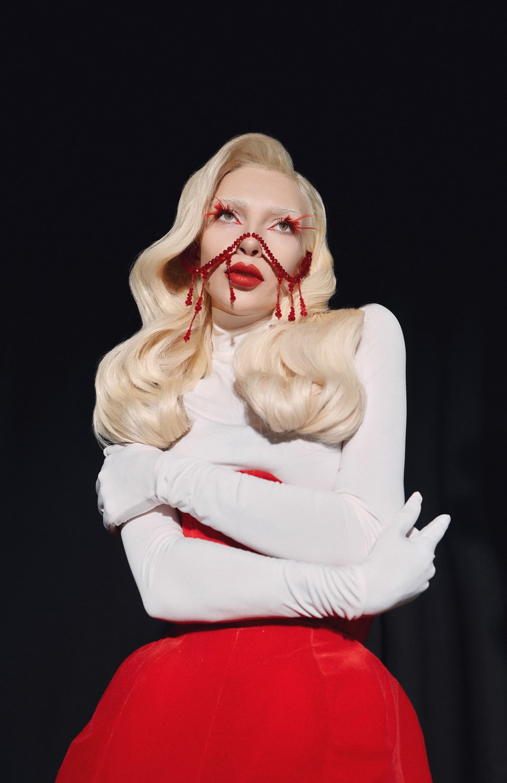 Fashion model with bold red makeup and glamorous hairstyle, wearing white and red.