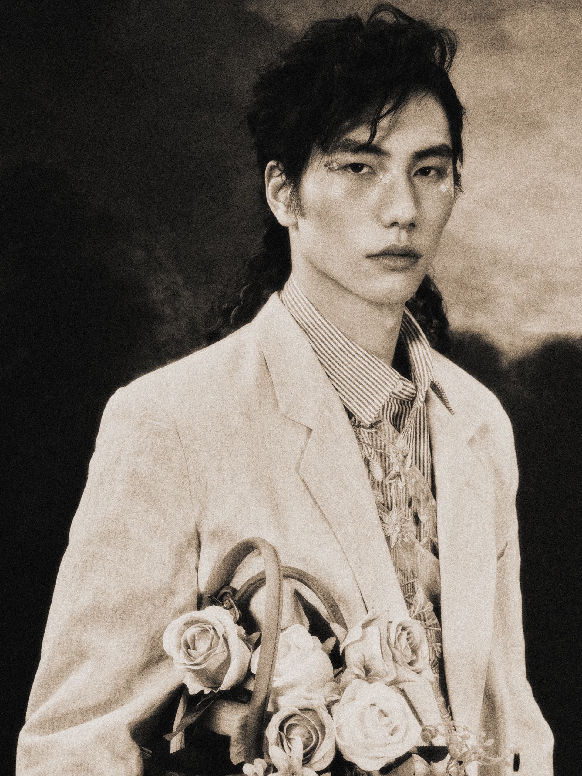 Vintage portrait: stylish person in a suit holding roses in a sepia-toned photo.