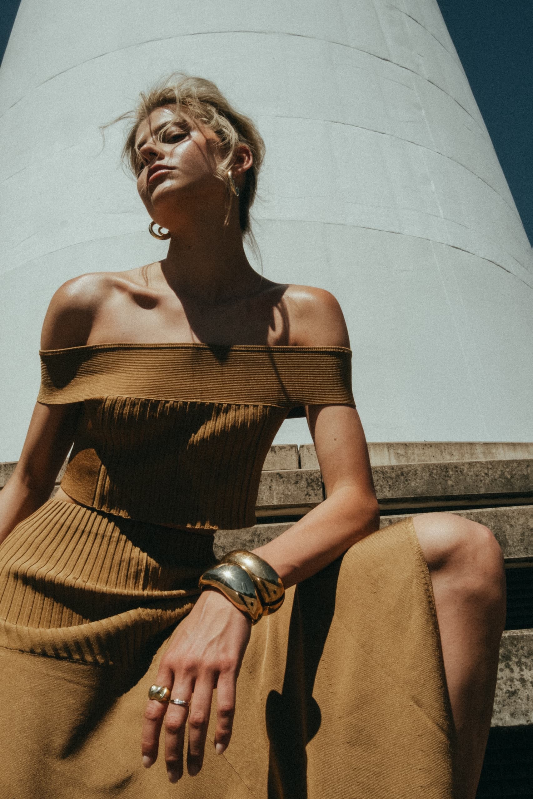 Woman in stylish brown outfit poses outdoors against modern architecture.