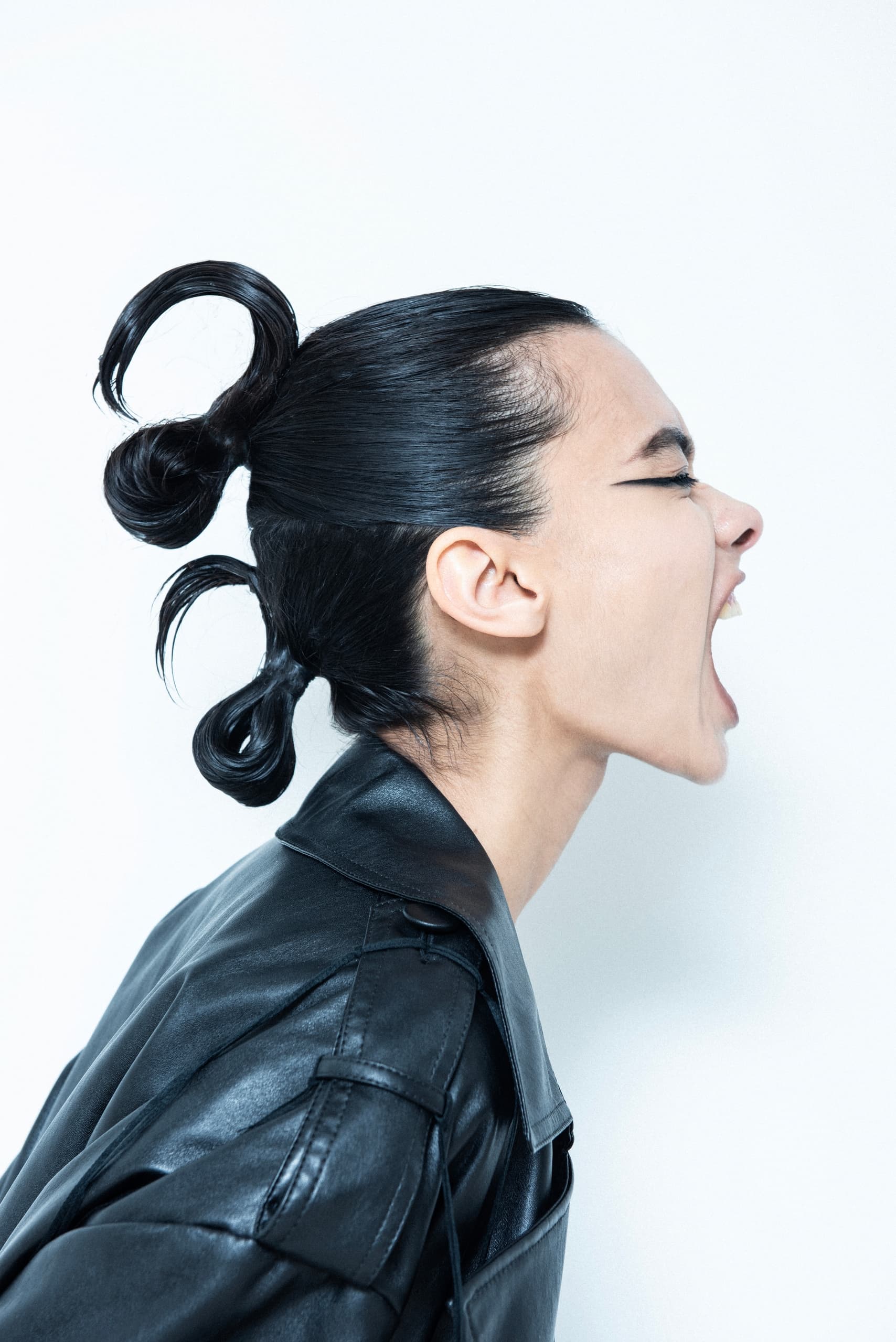 Profile of person with unique hairstyle and leather jacket, expressing emotion.