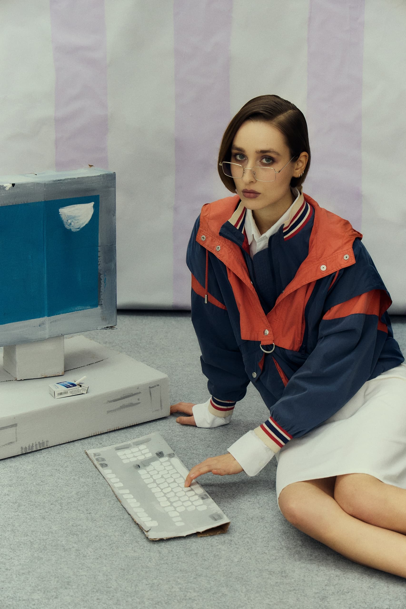 Woman in vintage jacket using a cardboard computer setup.
