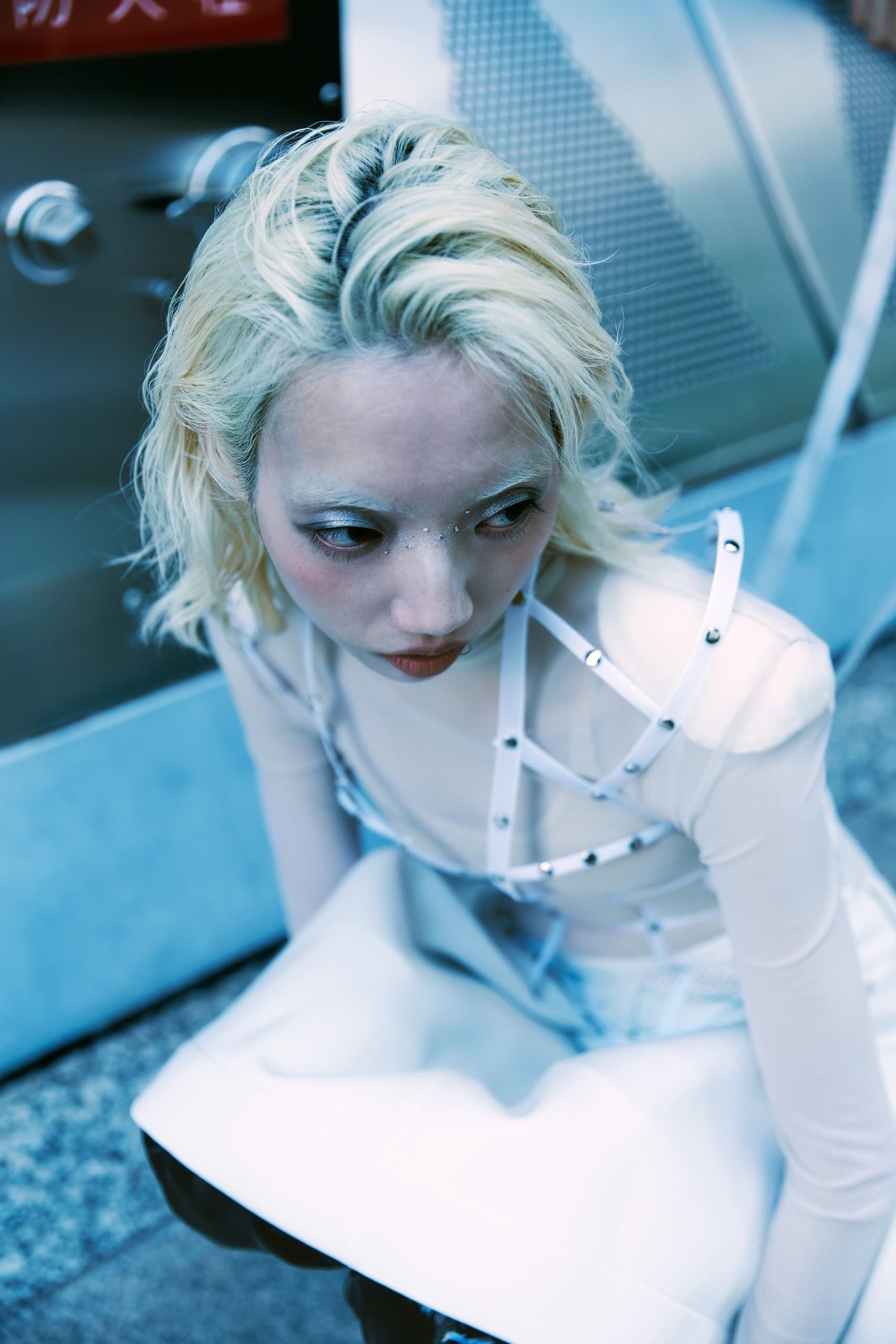 Fashionable person in edgy white outfit with modern urban backdrop.
