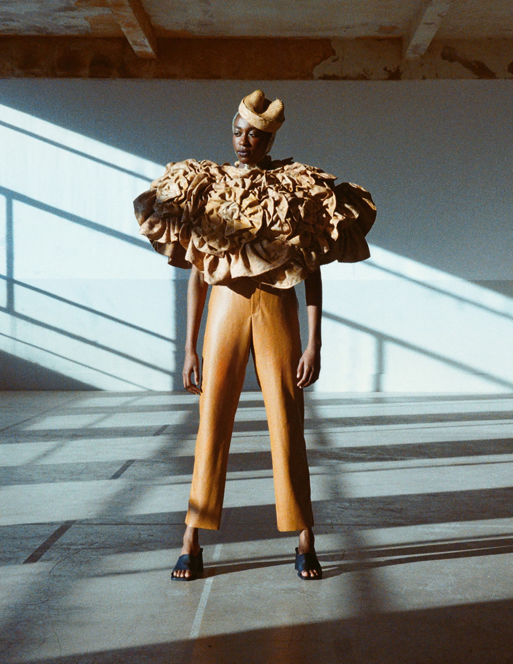 Fashion model in avant-garde outfit with textured top and structured pants.