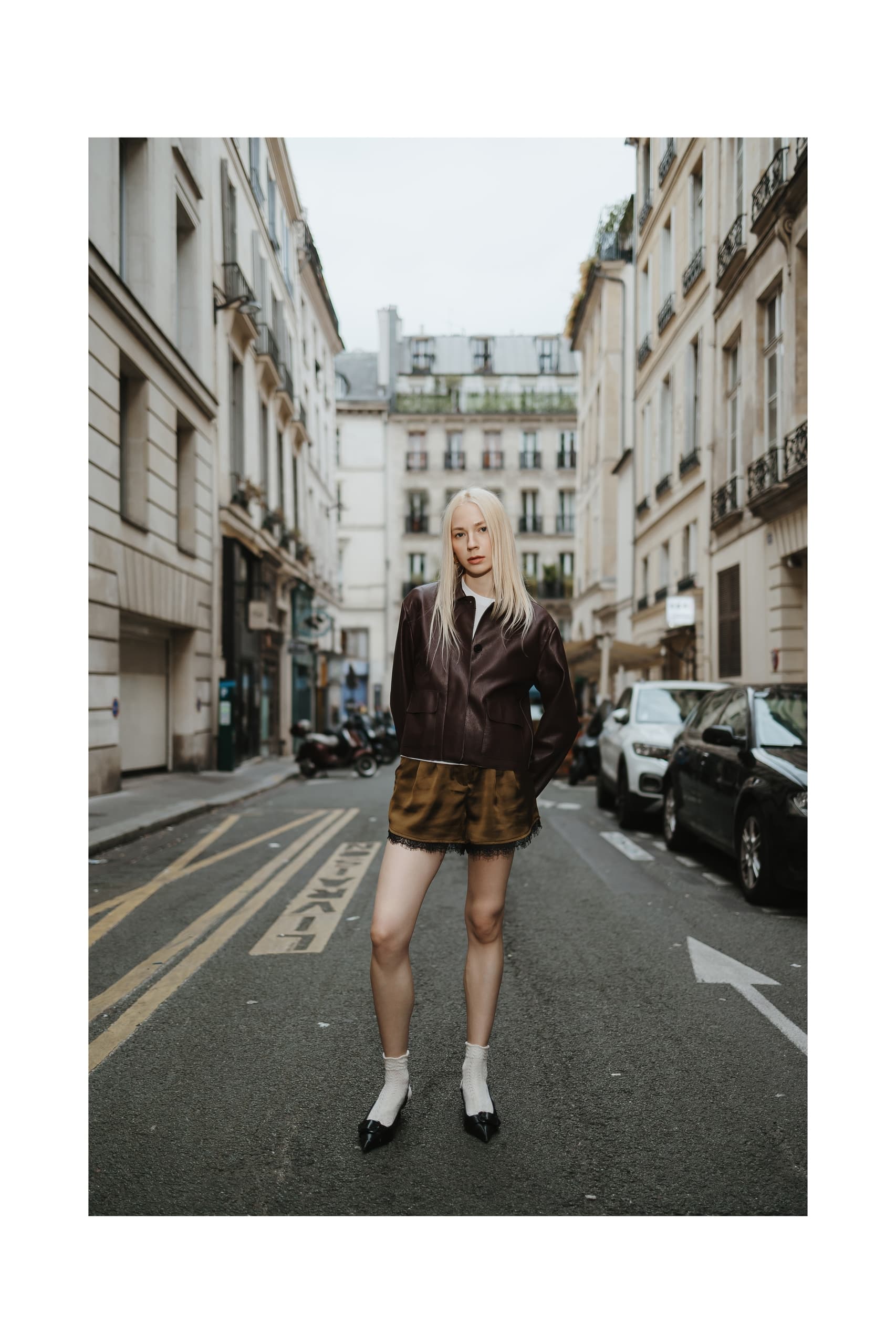 Fashionable woman in urban street, wearing a chic brown jacket and shorts.