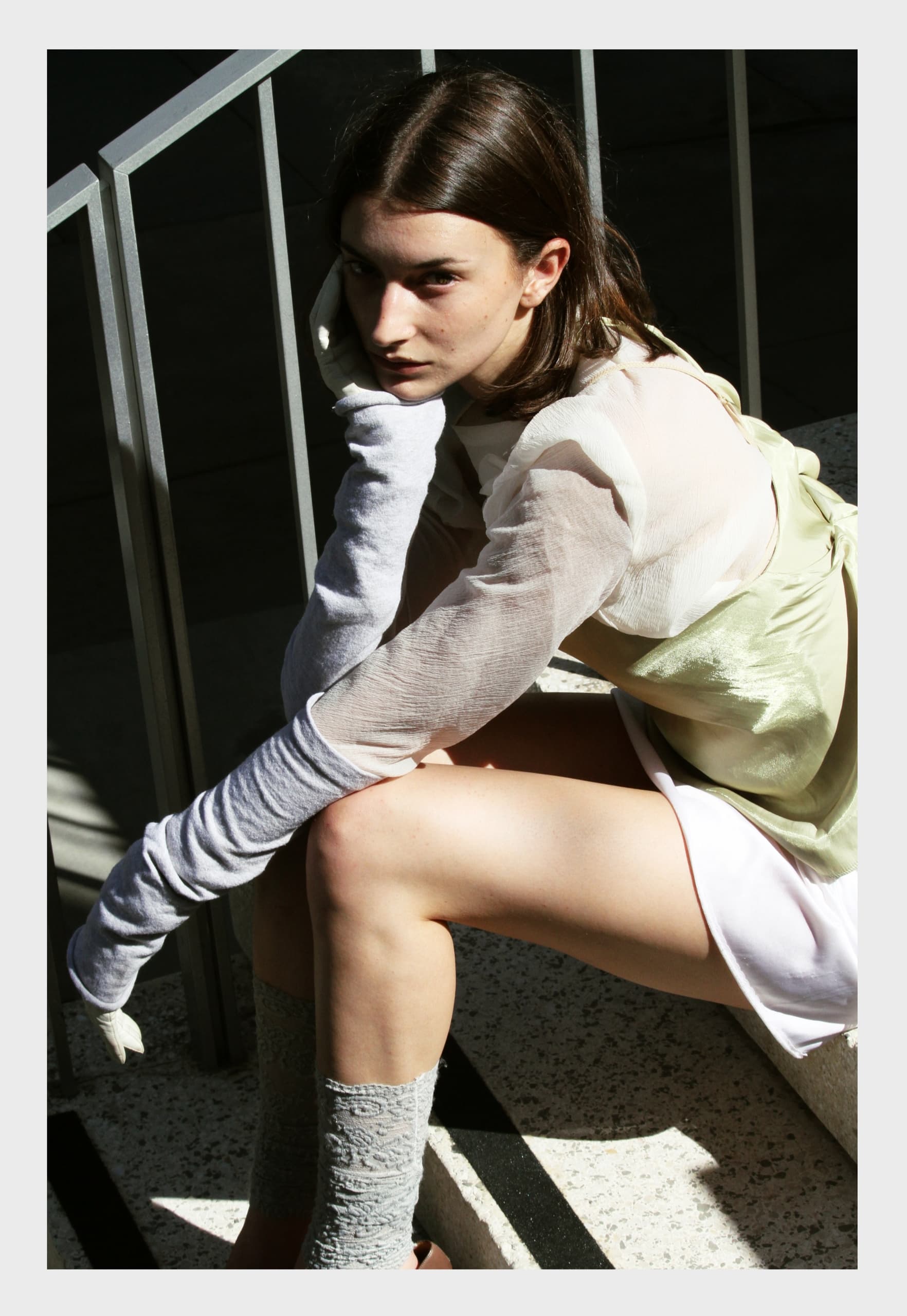 Fashionable woman in sheer top with long gloves sitting on stairs.