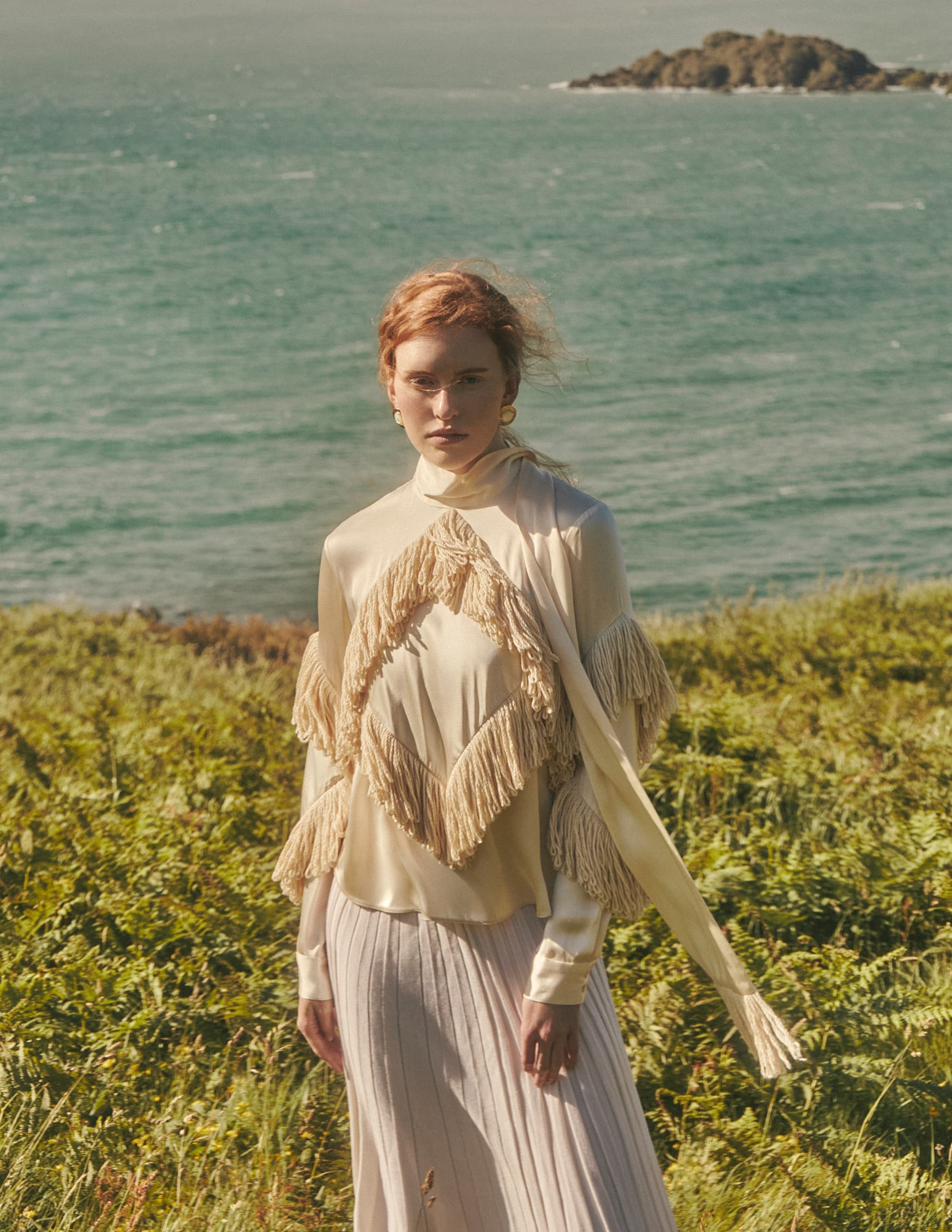Woman in elegant outfit standing by the ocean on a sunny day