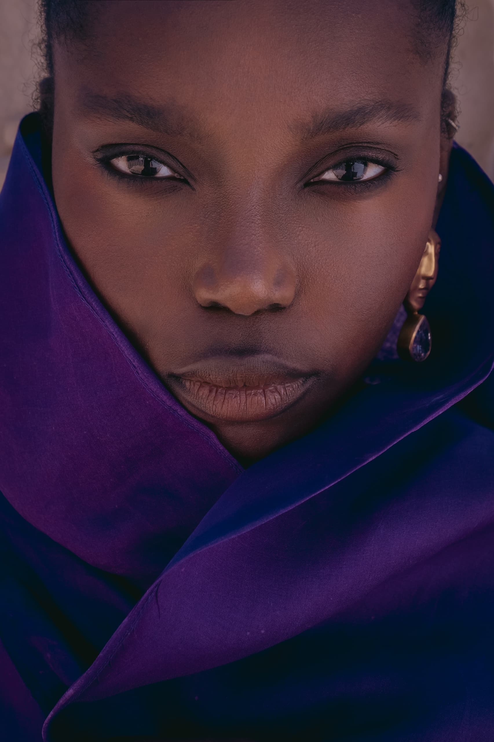 Woman in purple scarf with bold, intense gaze.