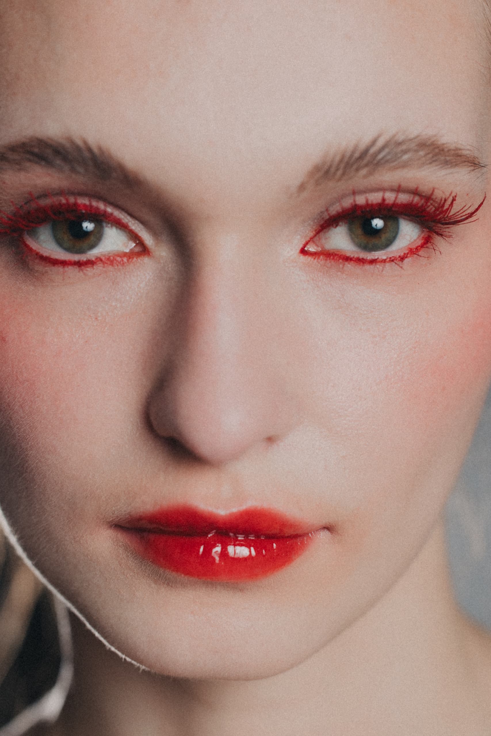 Close-up of a model with red eyeliner and lipstick, bold makeup look.