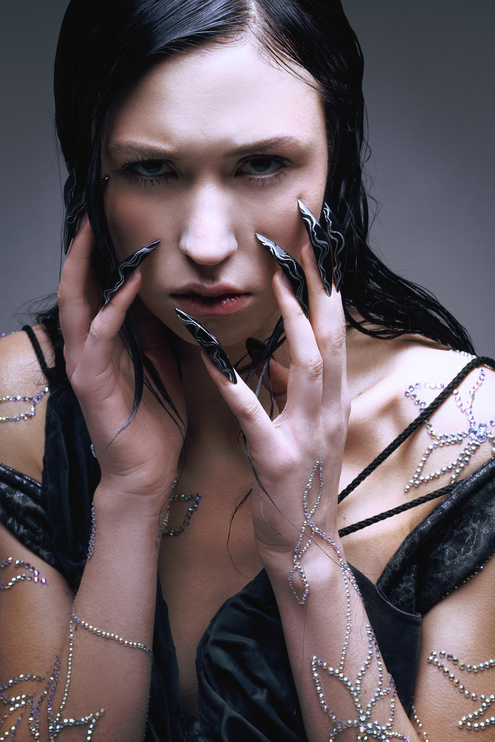 Mysterious woman with artistic long nails and intricate body art.