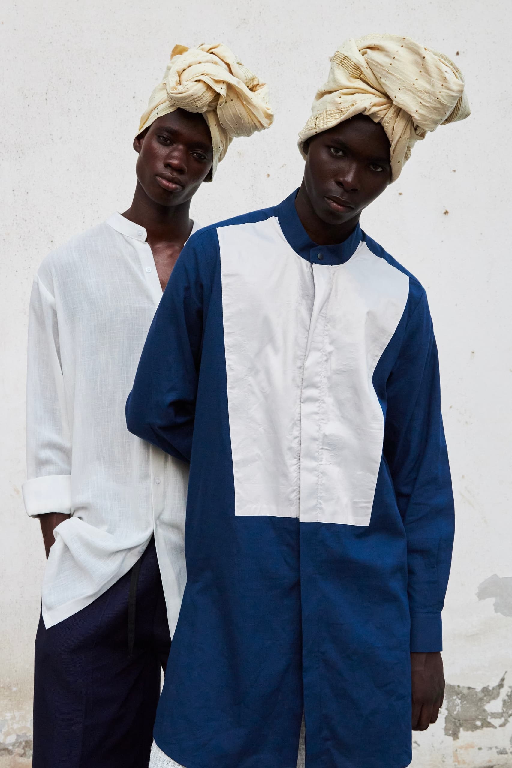 Two models in turban-style headwear and stylish shirts against a simple background.