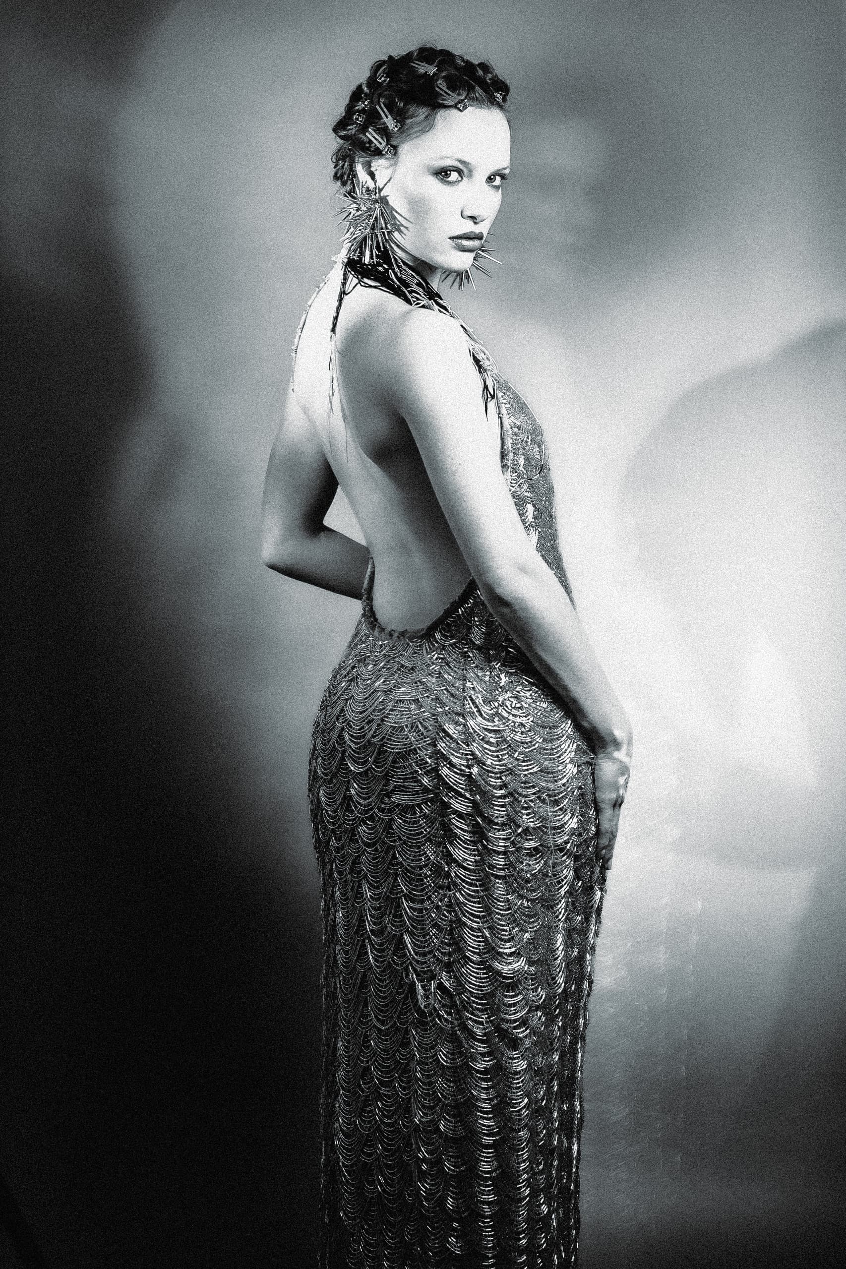 Elegant woman in vintage gown, dramatic pose in black and white photography.