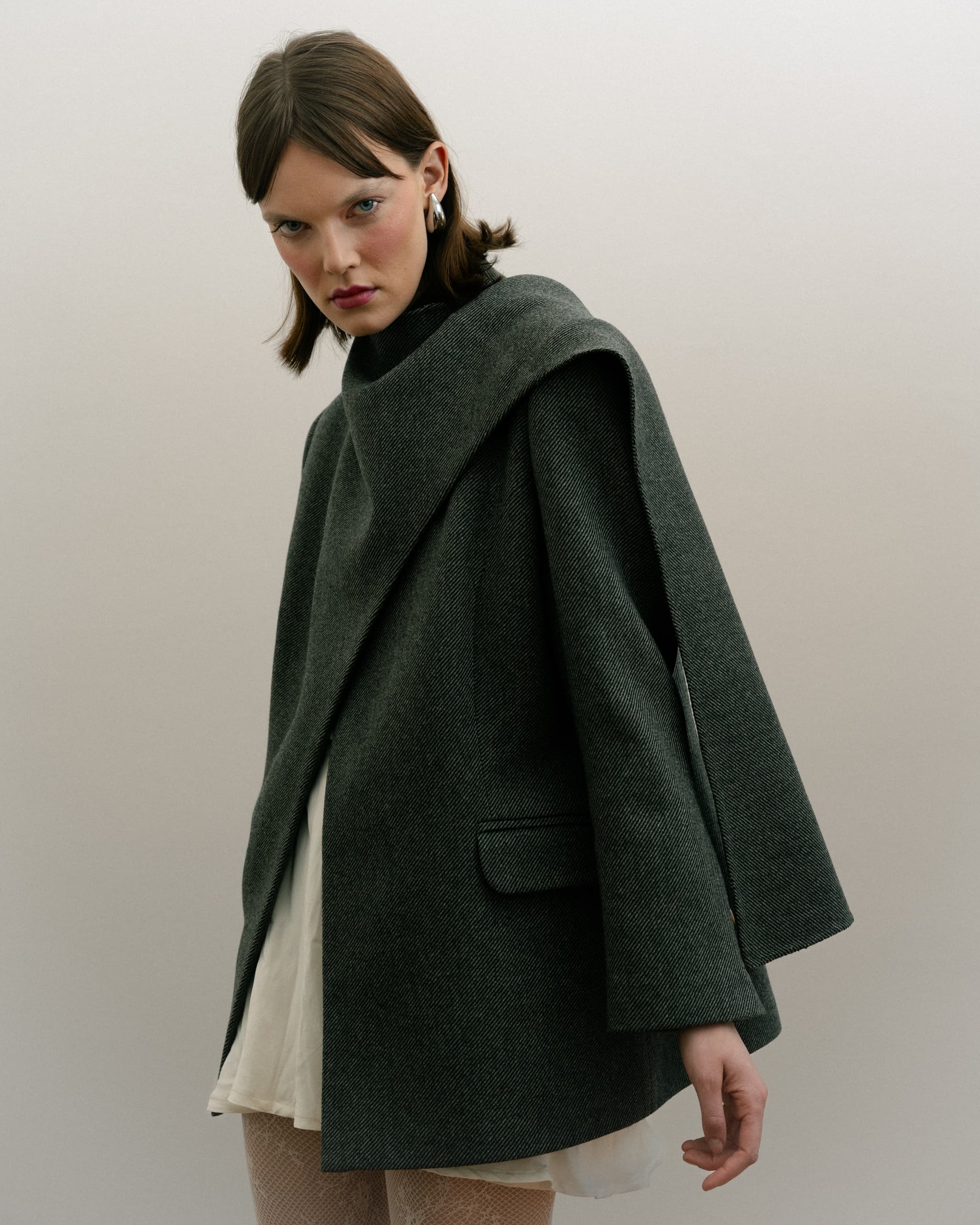 Model in a stylish gray coat with unique layered design.