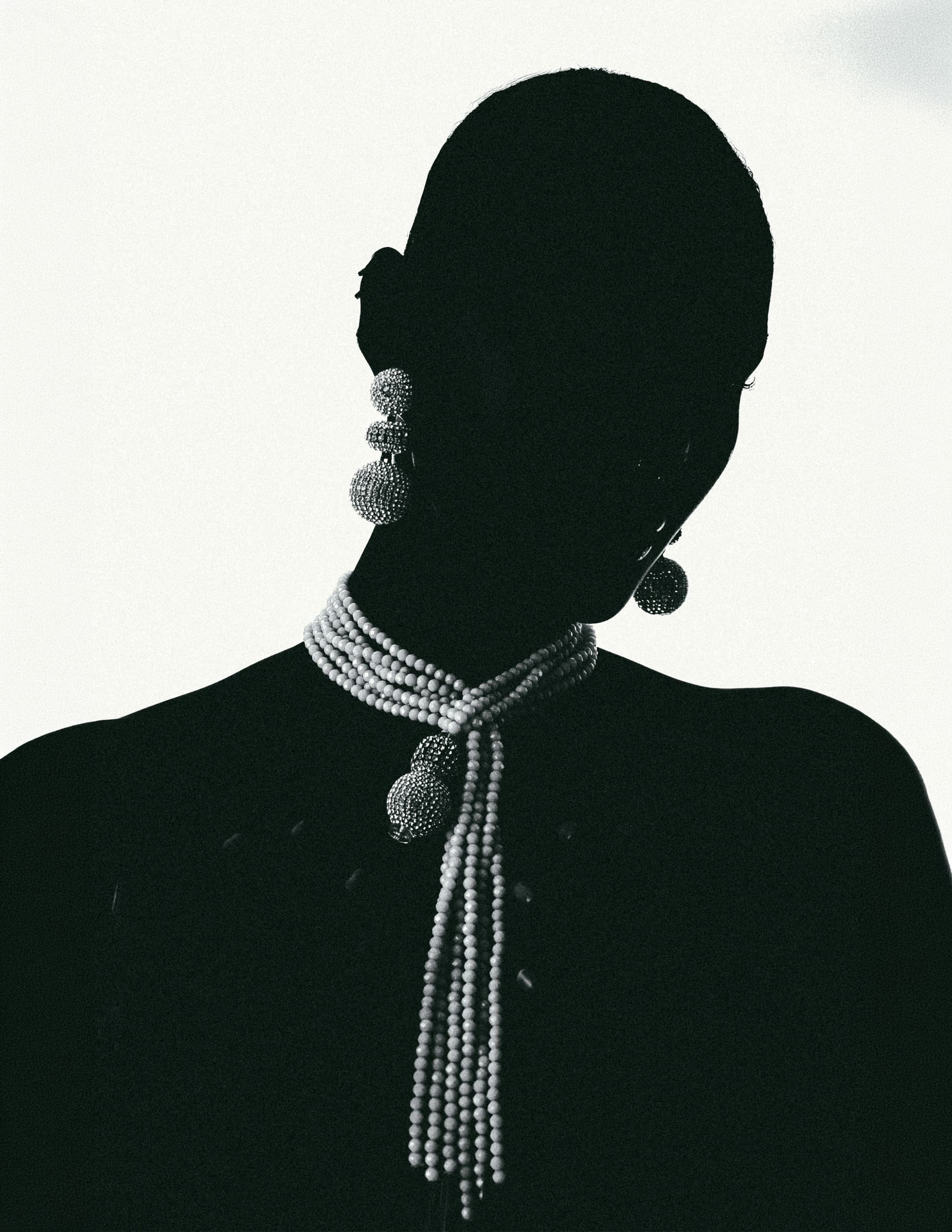 Silhouette in elegant pearl jewelry, artistic black and white photograph.