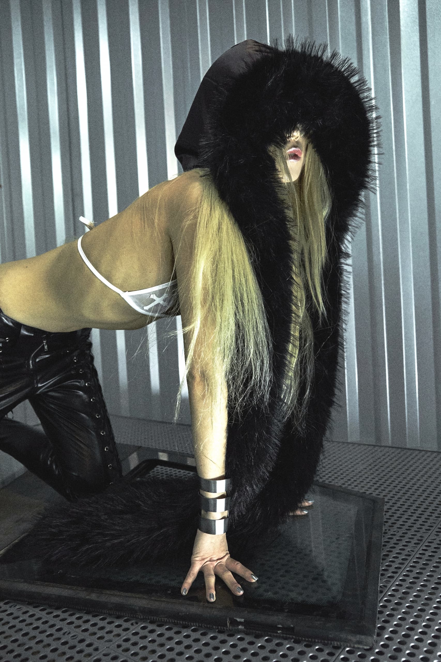 Edgy fashion: woman in fur hood and leather, striking pose.
