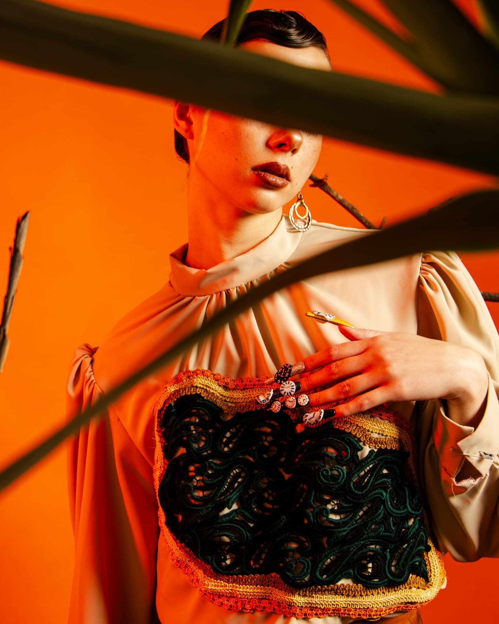 Fashion model in elegant attire with bold orange background and artistic flair.