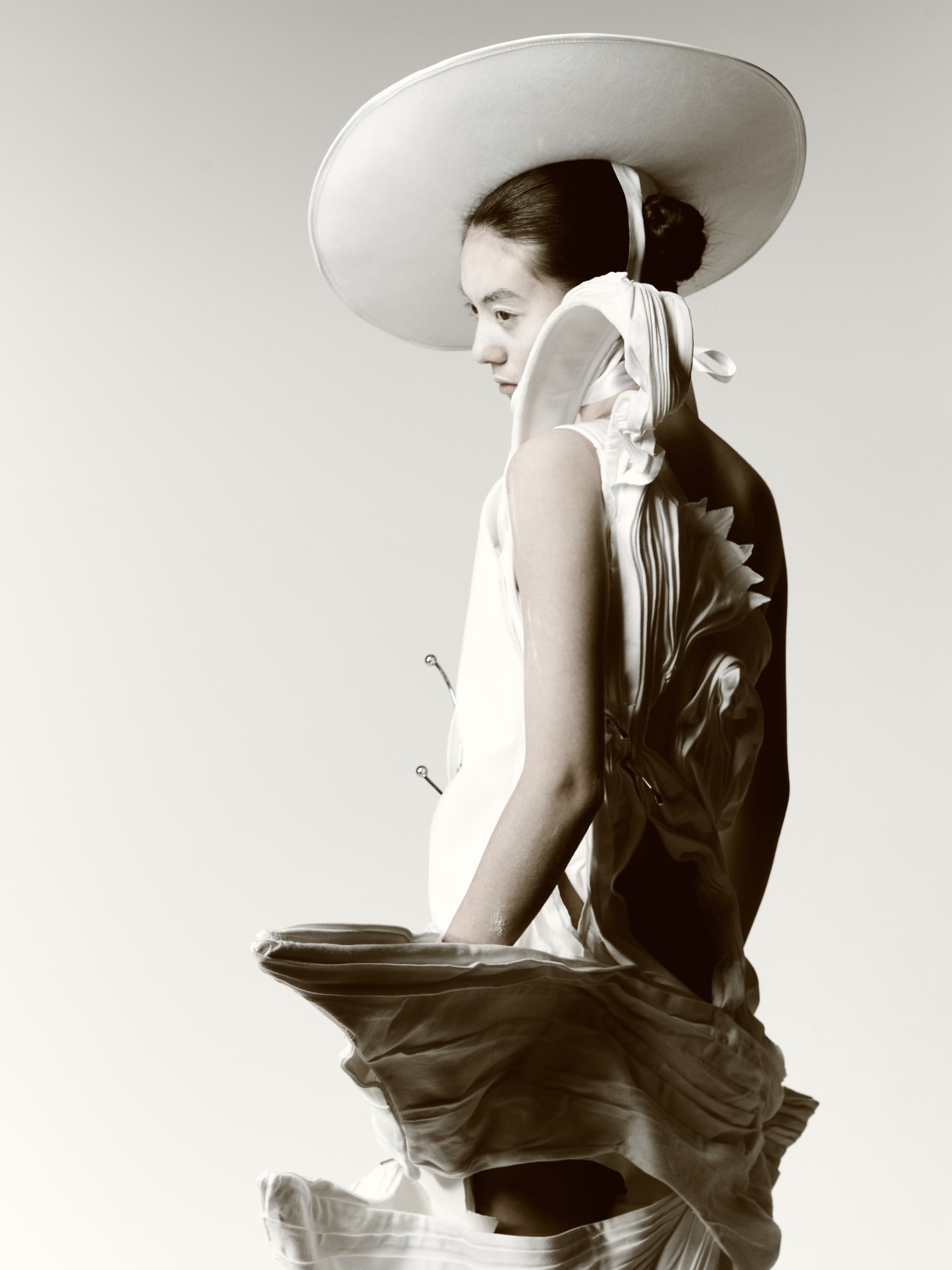 Fashion model in artistic dress and hat, monochrome elegance.