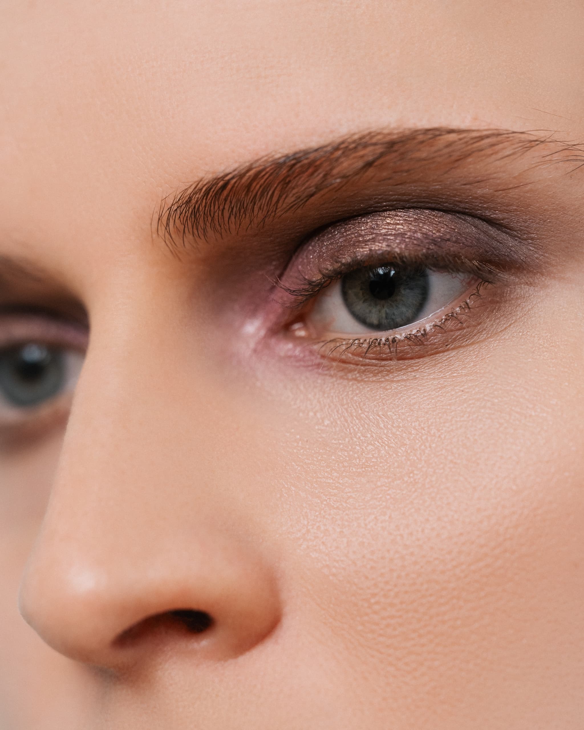 Close-up of eye with shimmering eyeshadow and well-groomed eyebrow.