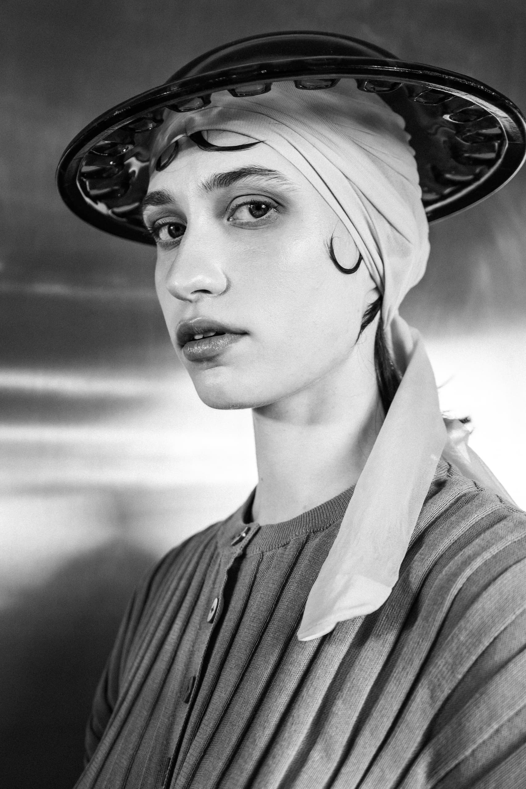 Black and white portrait of a person wearing a hat and headscarf, vintage style.