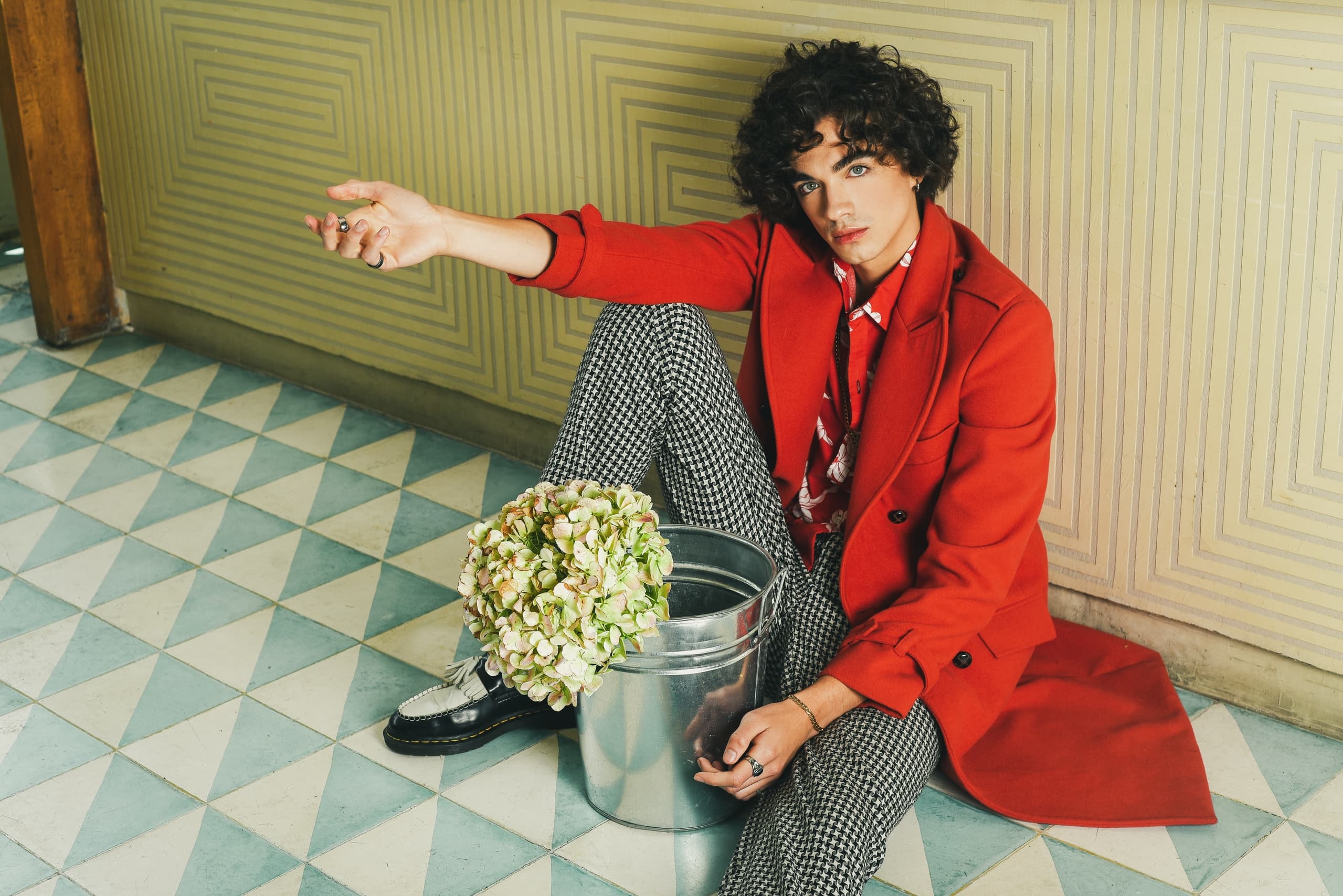 Stylish person in red jacket with flowers by geometric wall pattern.