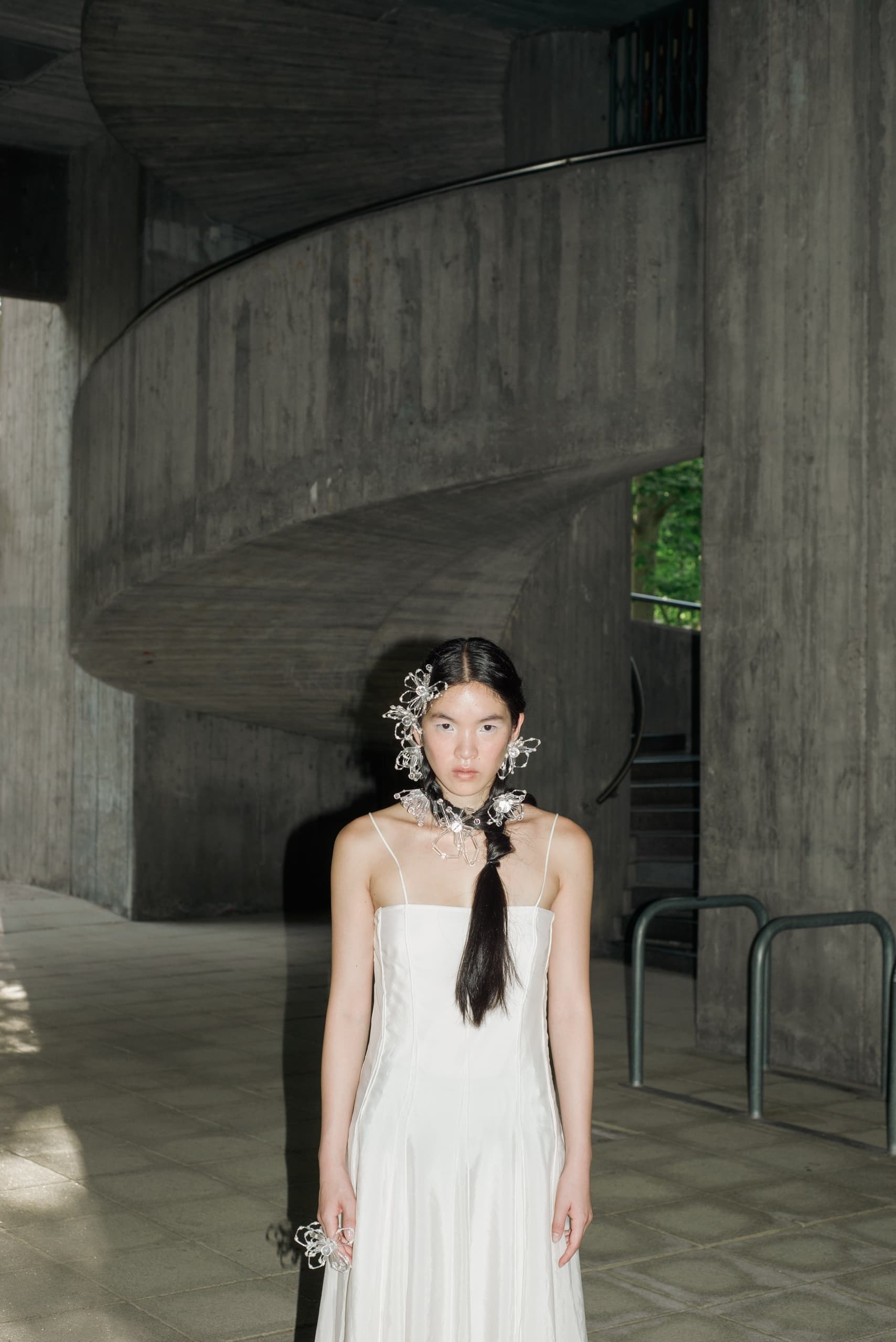 Woman in elegant white dress with floral accessories indoors.