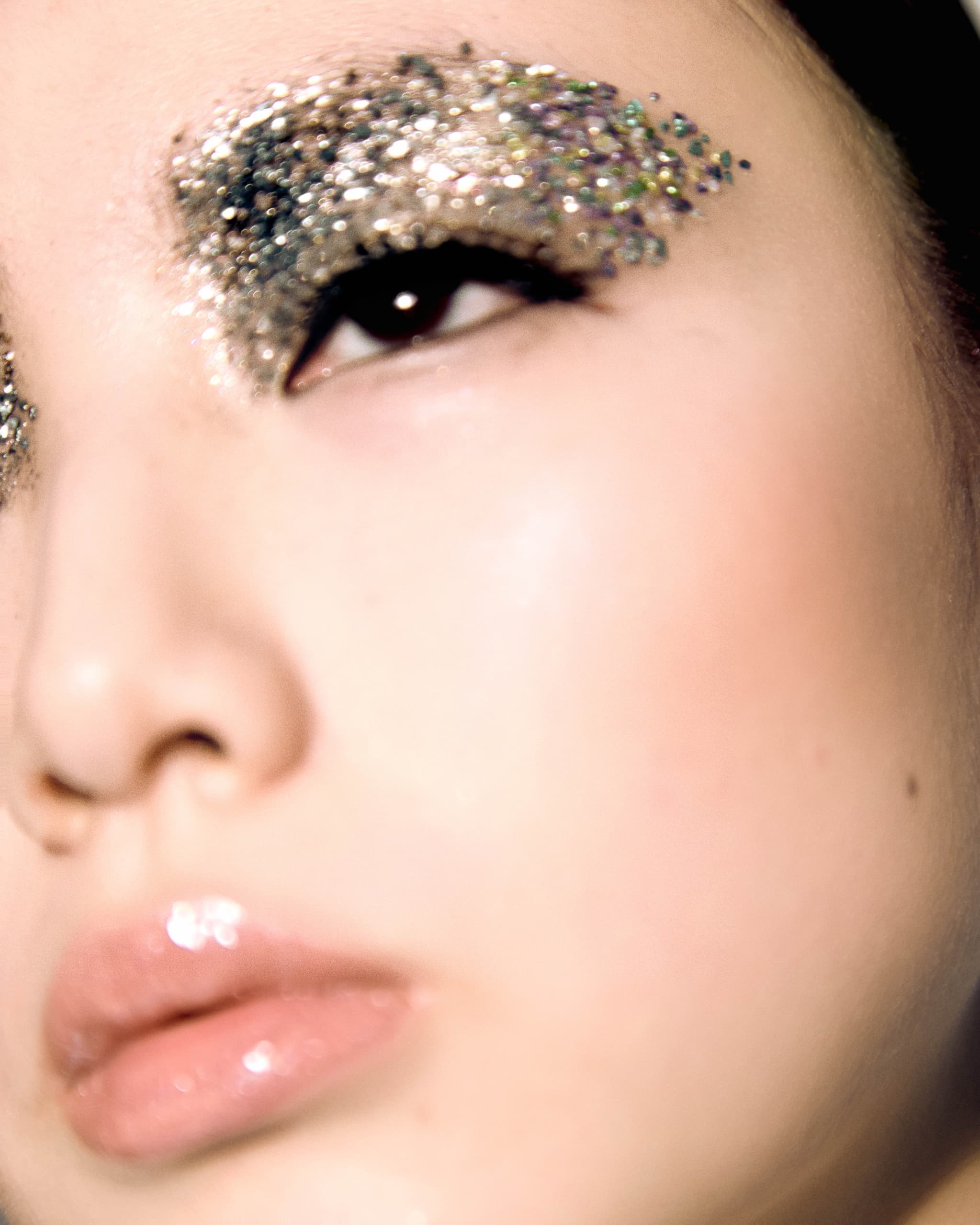 Close-up of glittery eye makeup and glossy lips.