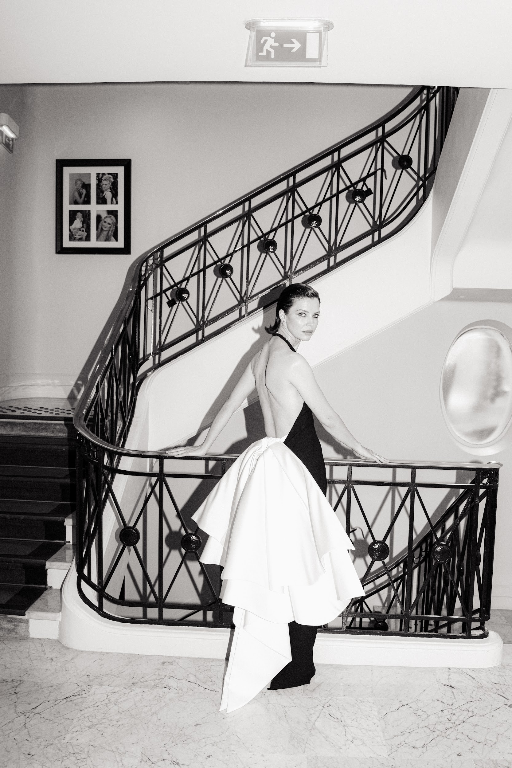 Elegant woman in black and white dress on a staircase, vintage style setting.