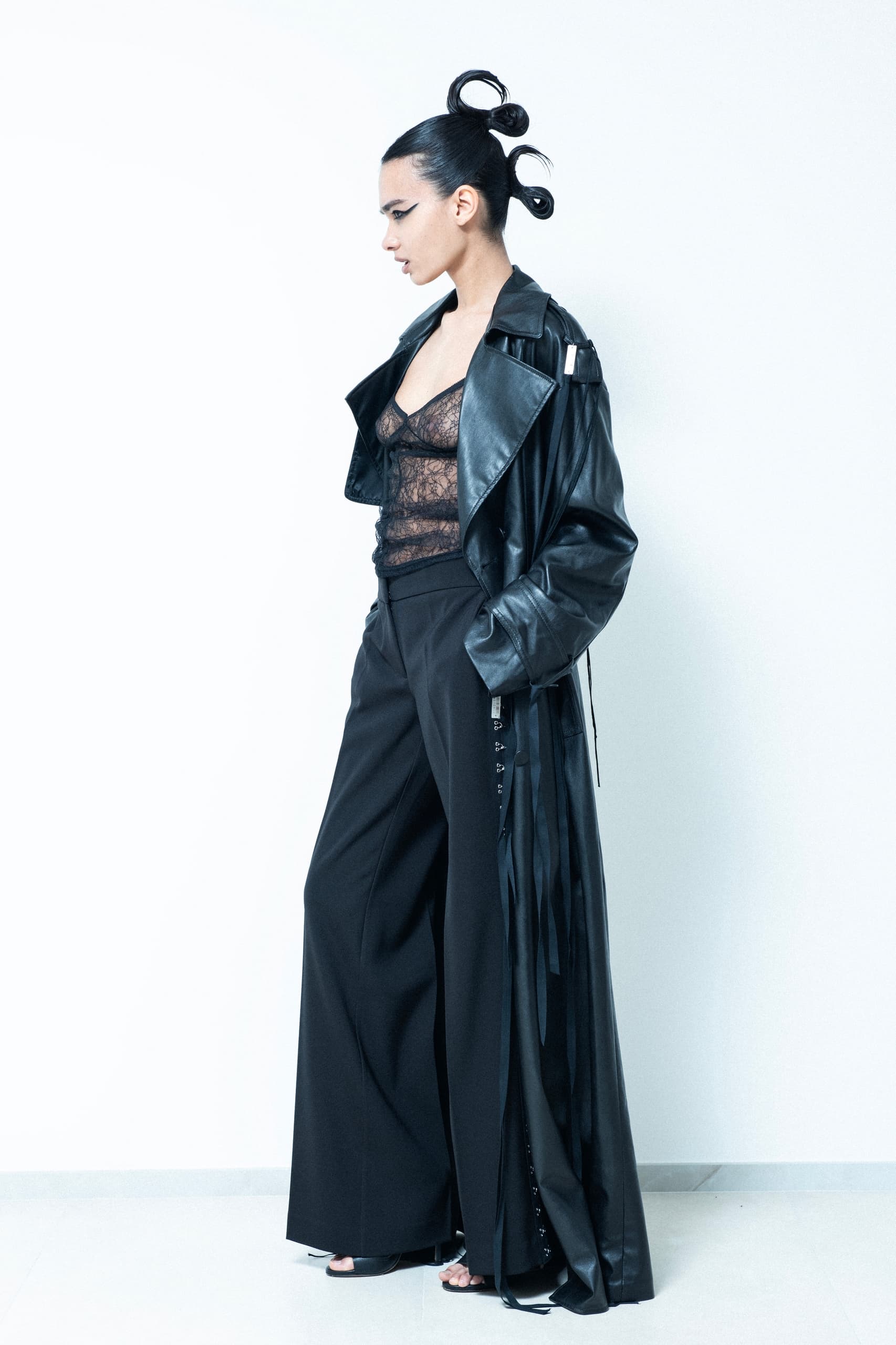 Fashion model in black leather coat and lace top, striking modern edgy pose.